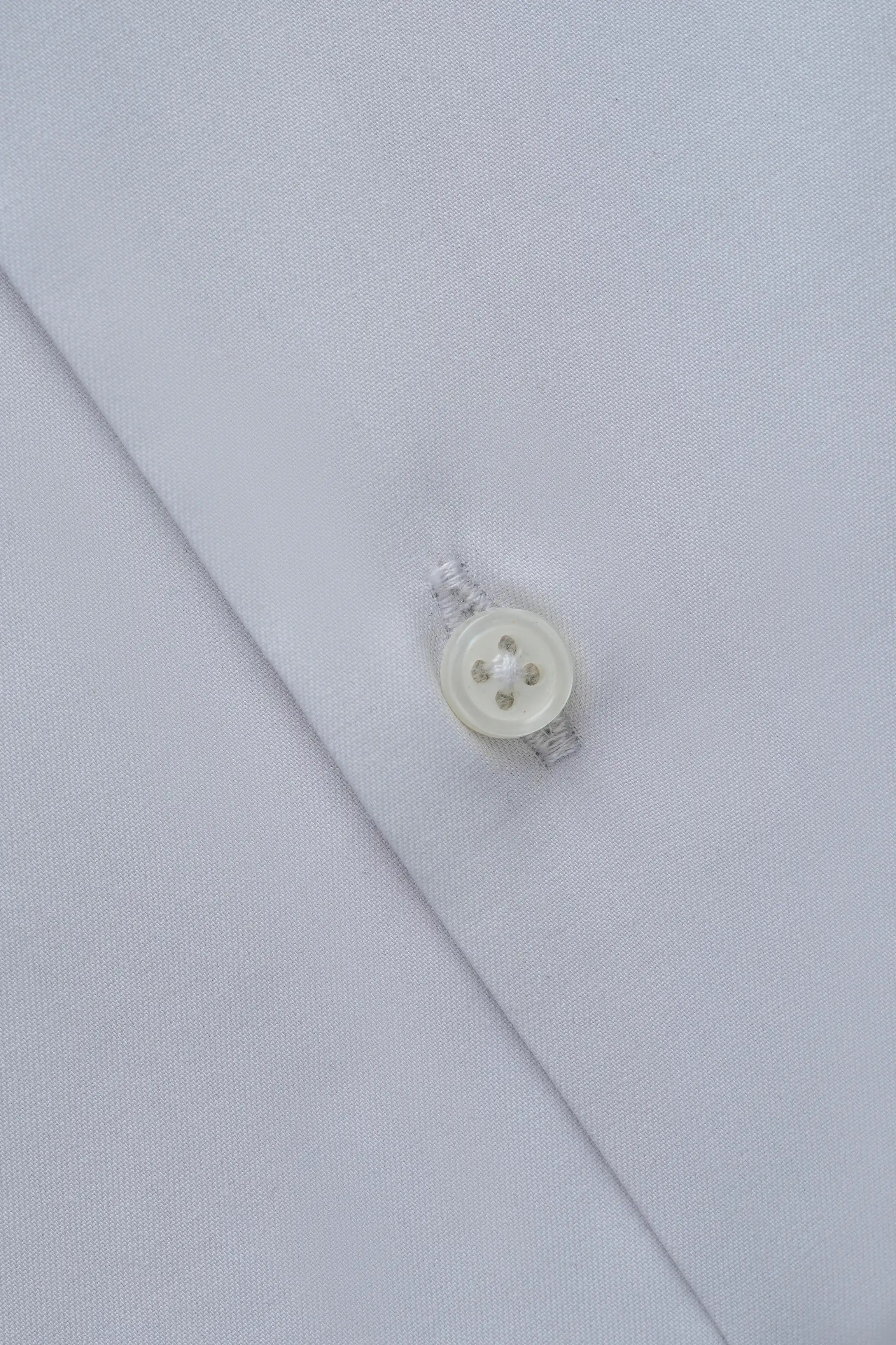 Light grey dress shirt detail with white round button and stitched placket