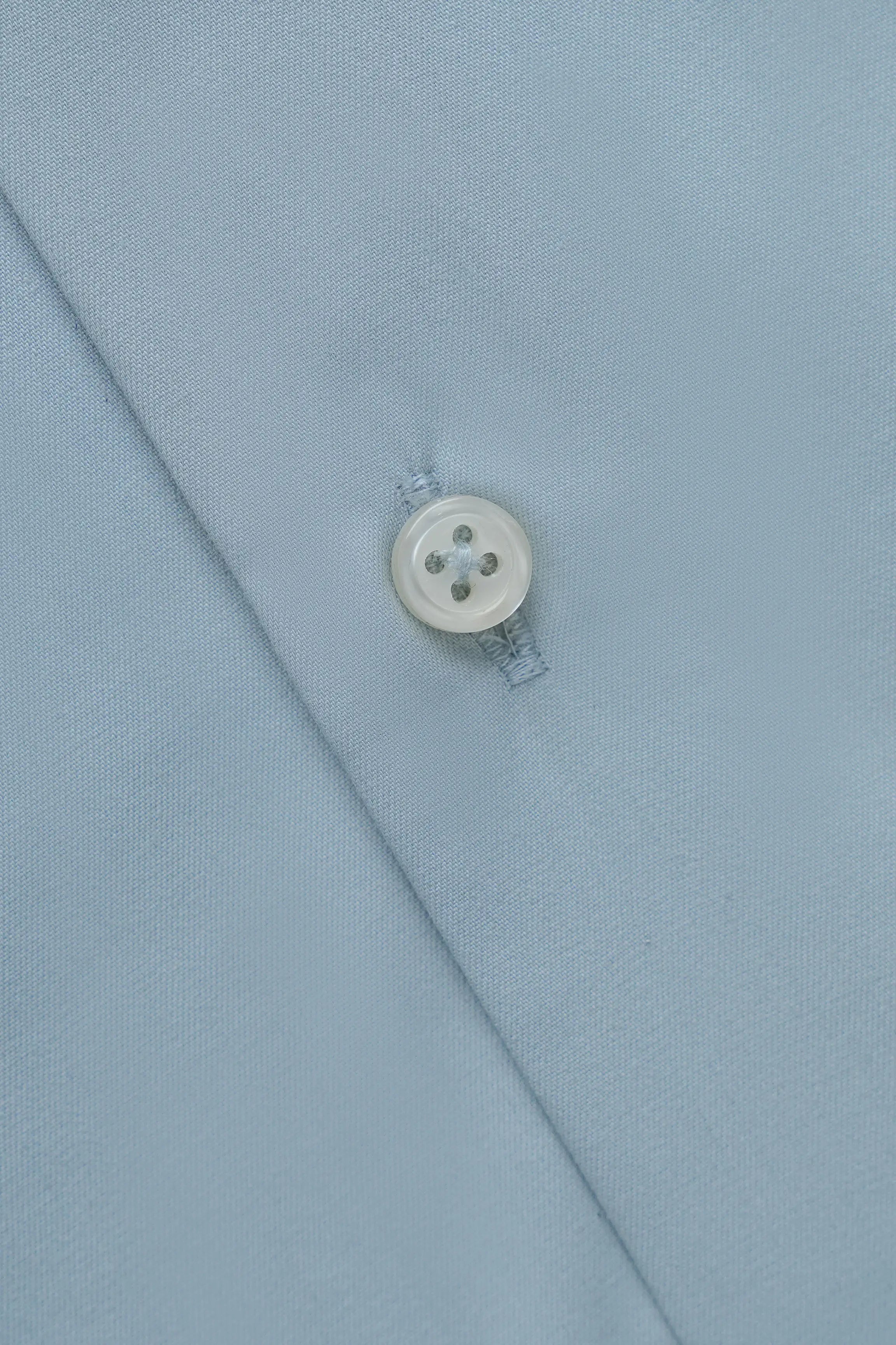 Dress shirt sleeve cuff detail with round button and stitched edge
