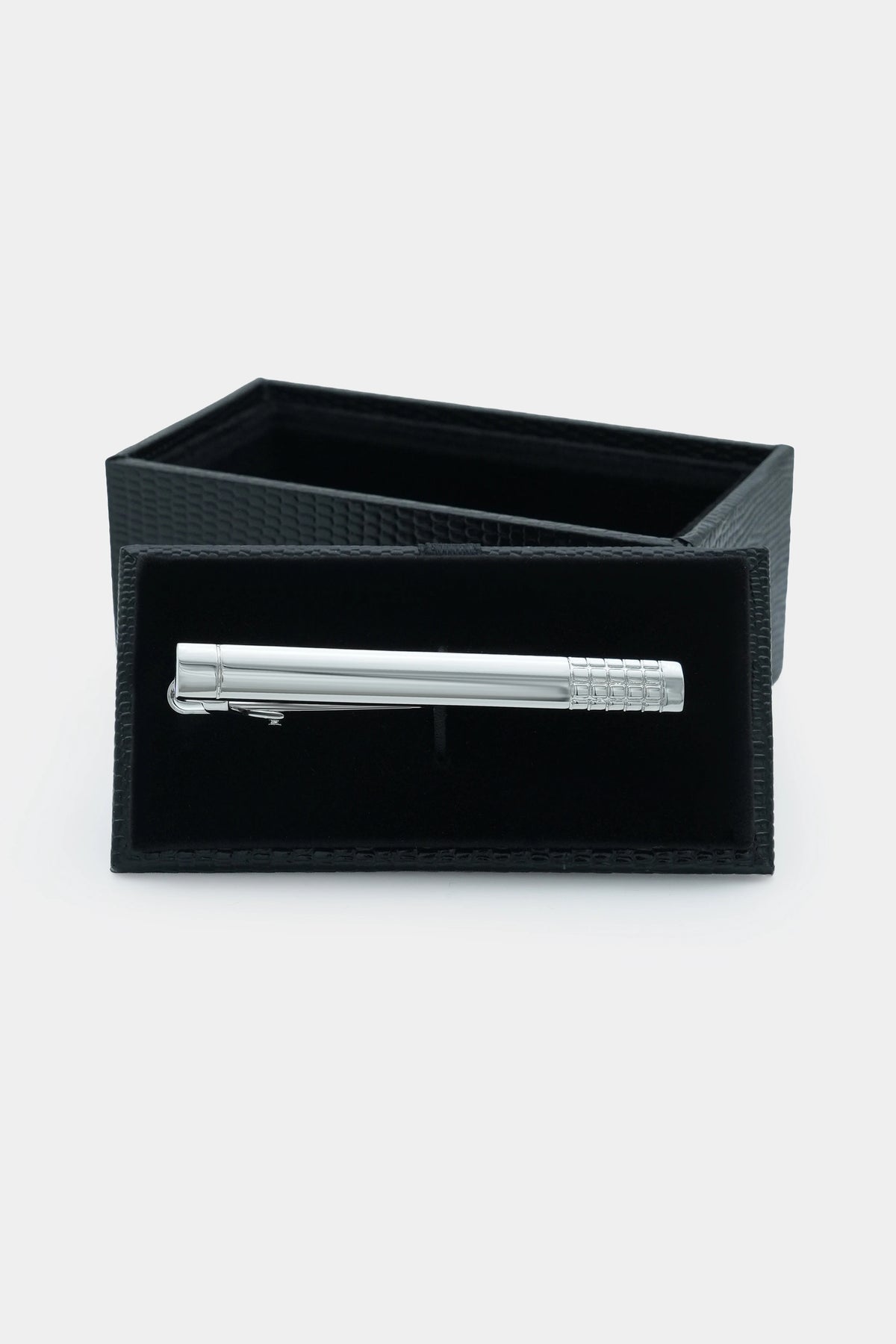 Silver tie pin inside a black fabric case with textured side panels