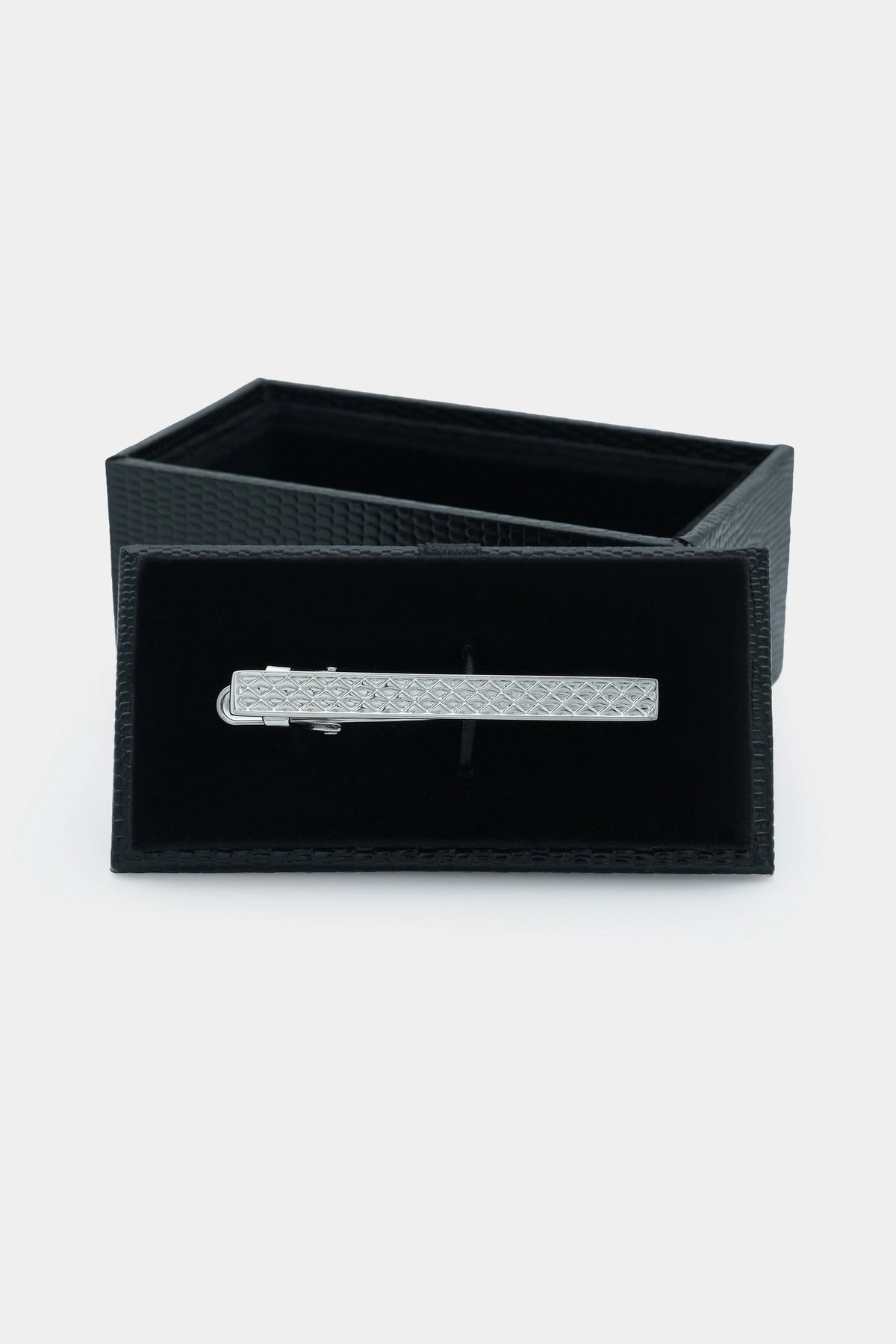 Silver tie pin resting on a black gift box with textured lining