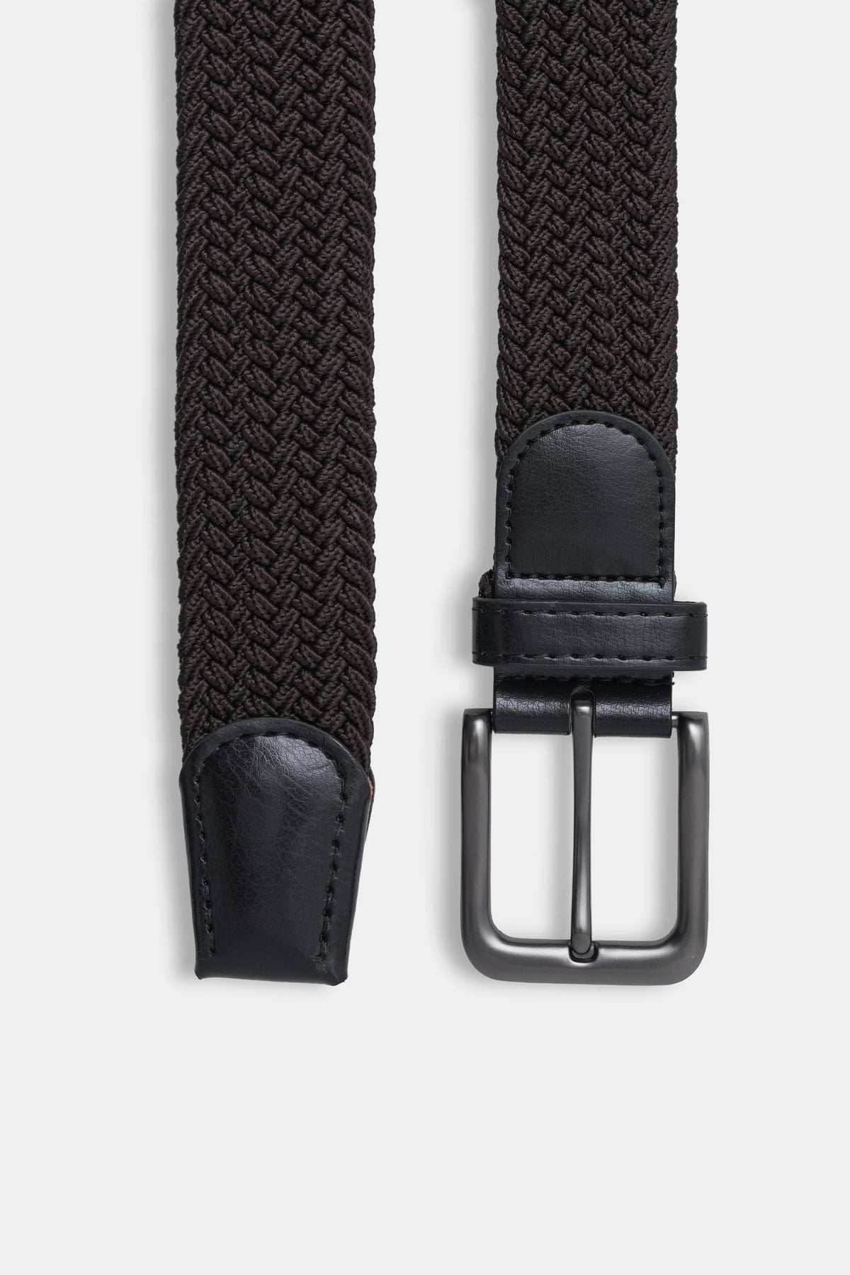 Detail of dark woven casual belt with silver buckle, black leather end, and keeper strap.