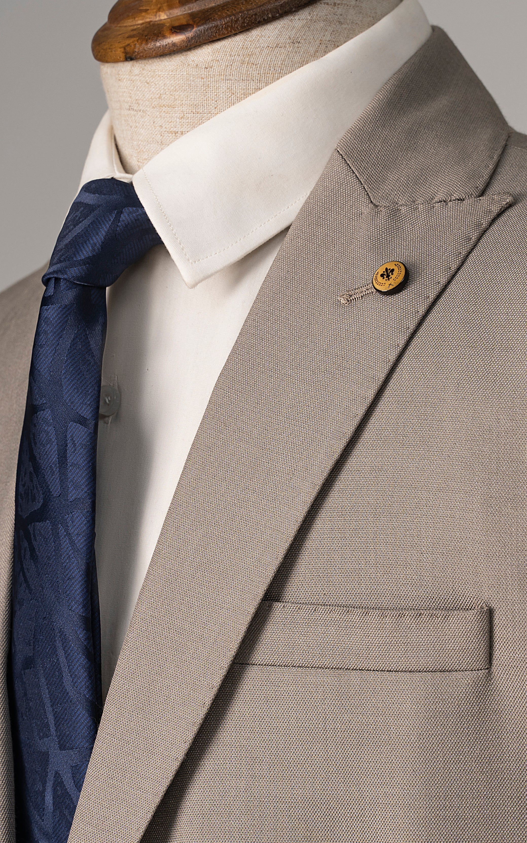 Beige suit jacket close-up with white shirt collar and blue patterned tie