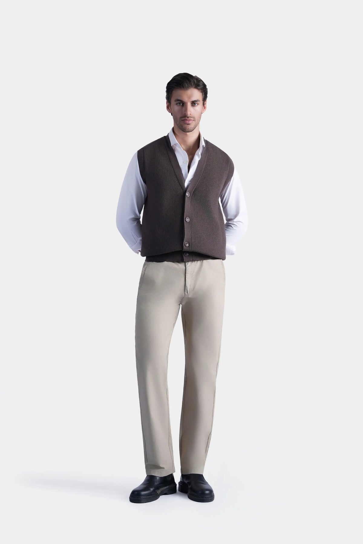 Brown V-neck sleeveless knit sweater vest with button front, worn over white shirt