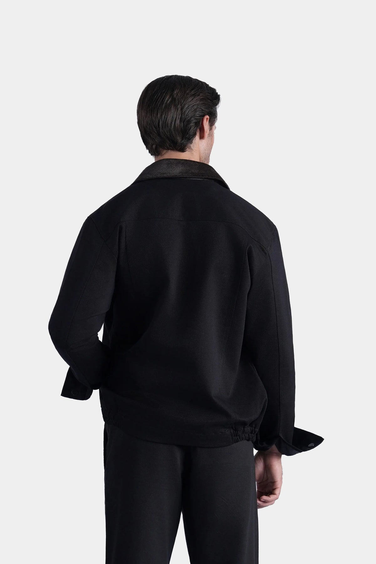 Men's black relaxed-fit long-sleeve jacket, back view with yoke and banded hem