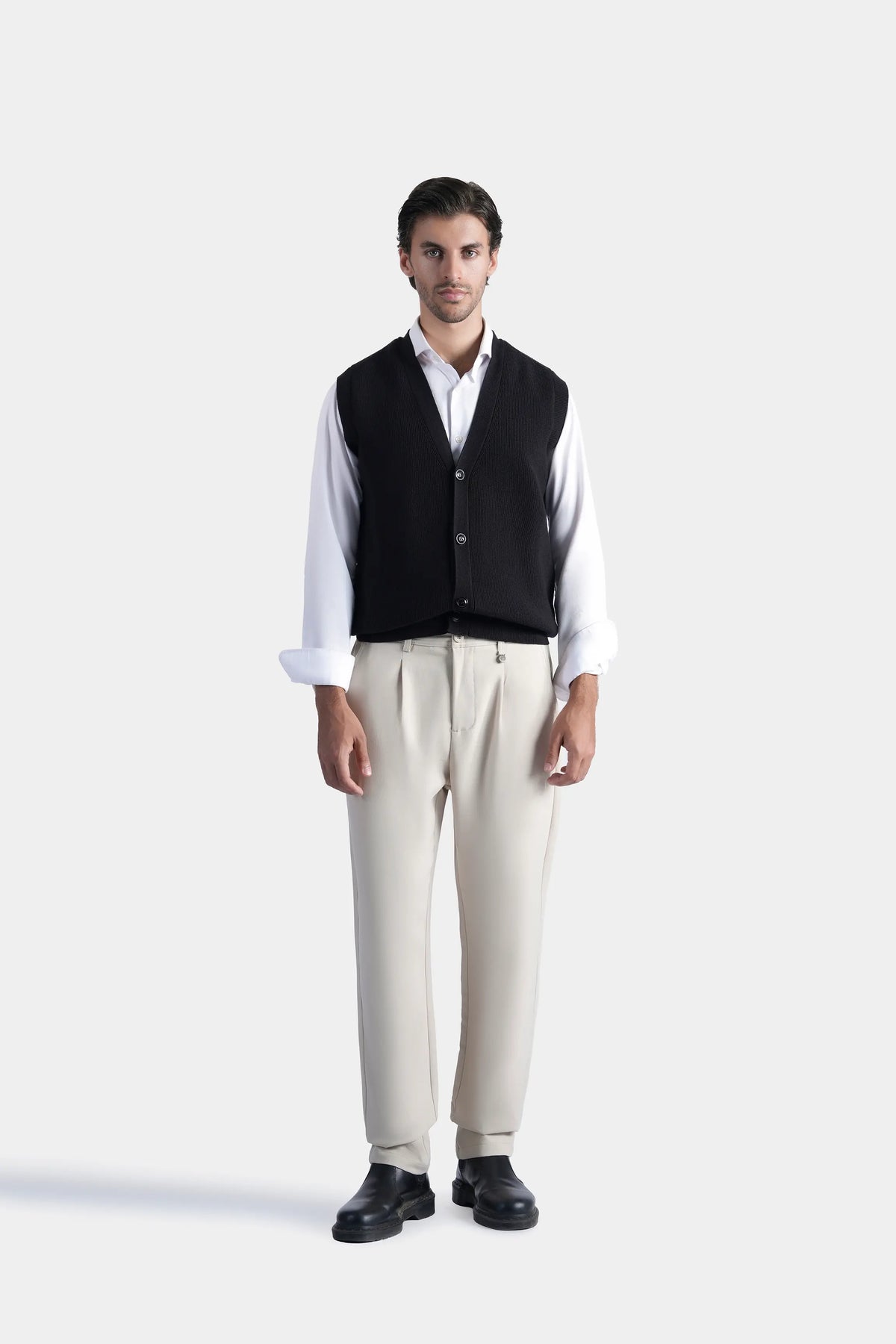 Black knit V-neck sleeveless sweater vest with button front, worn over shirt