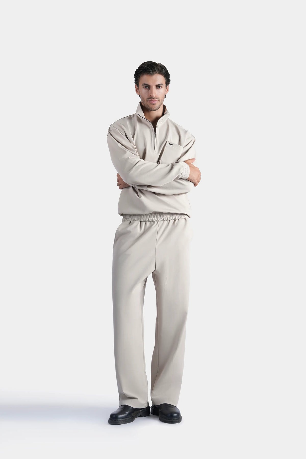 Beige quarter-zip mock neck sweatshirt with long sleeves, arms crossed
