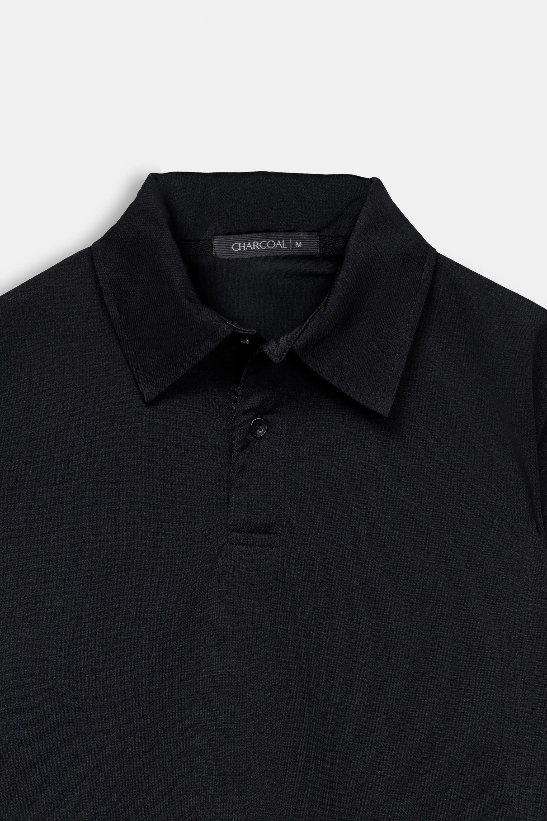 Black polo shirt collar and front placket with small logo label at neckline