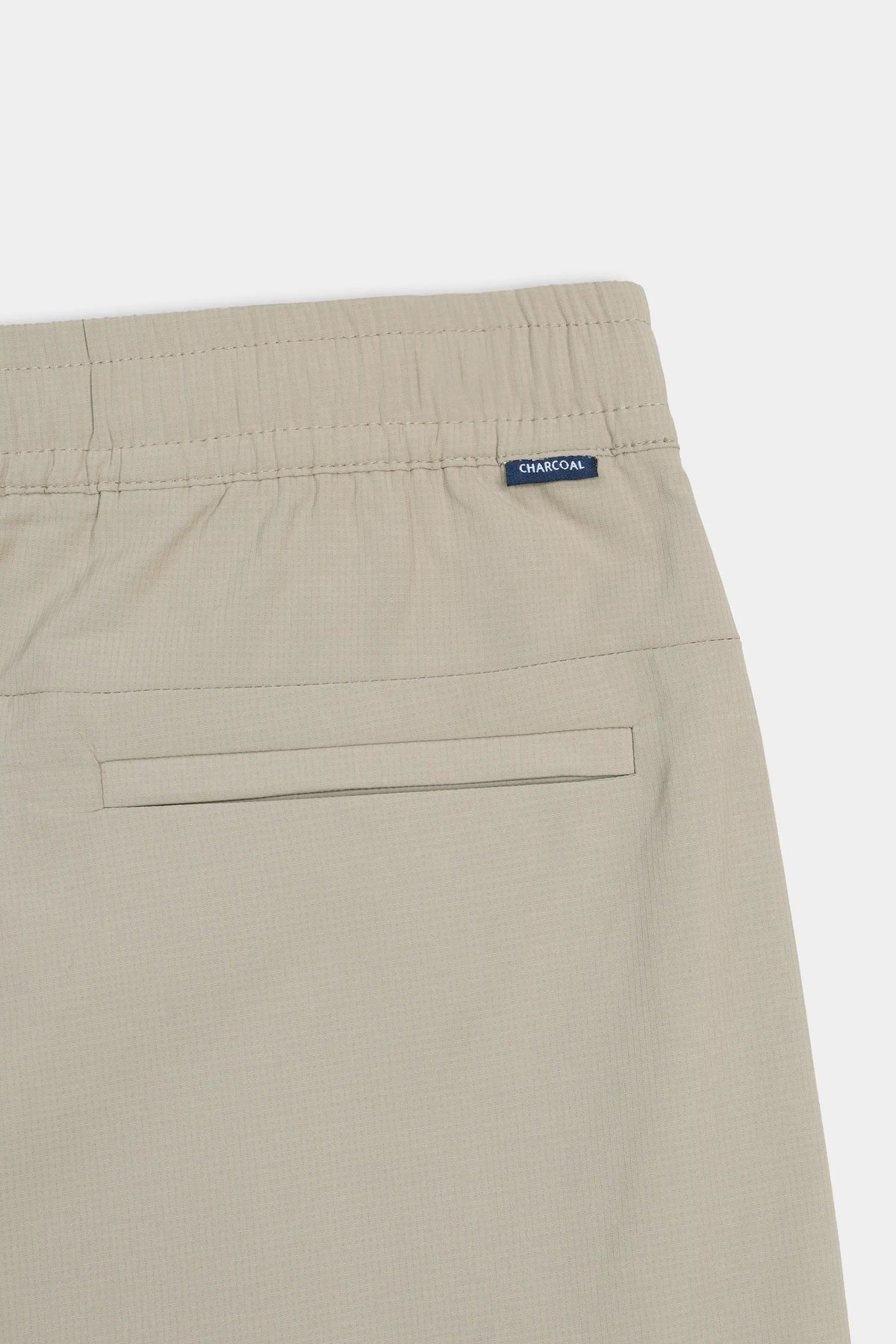 Beige trousers back pocket area with label reading CHARCOAL