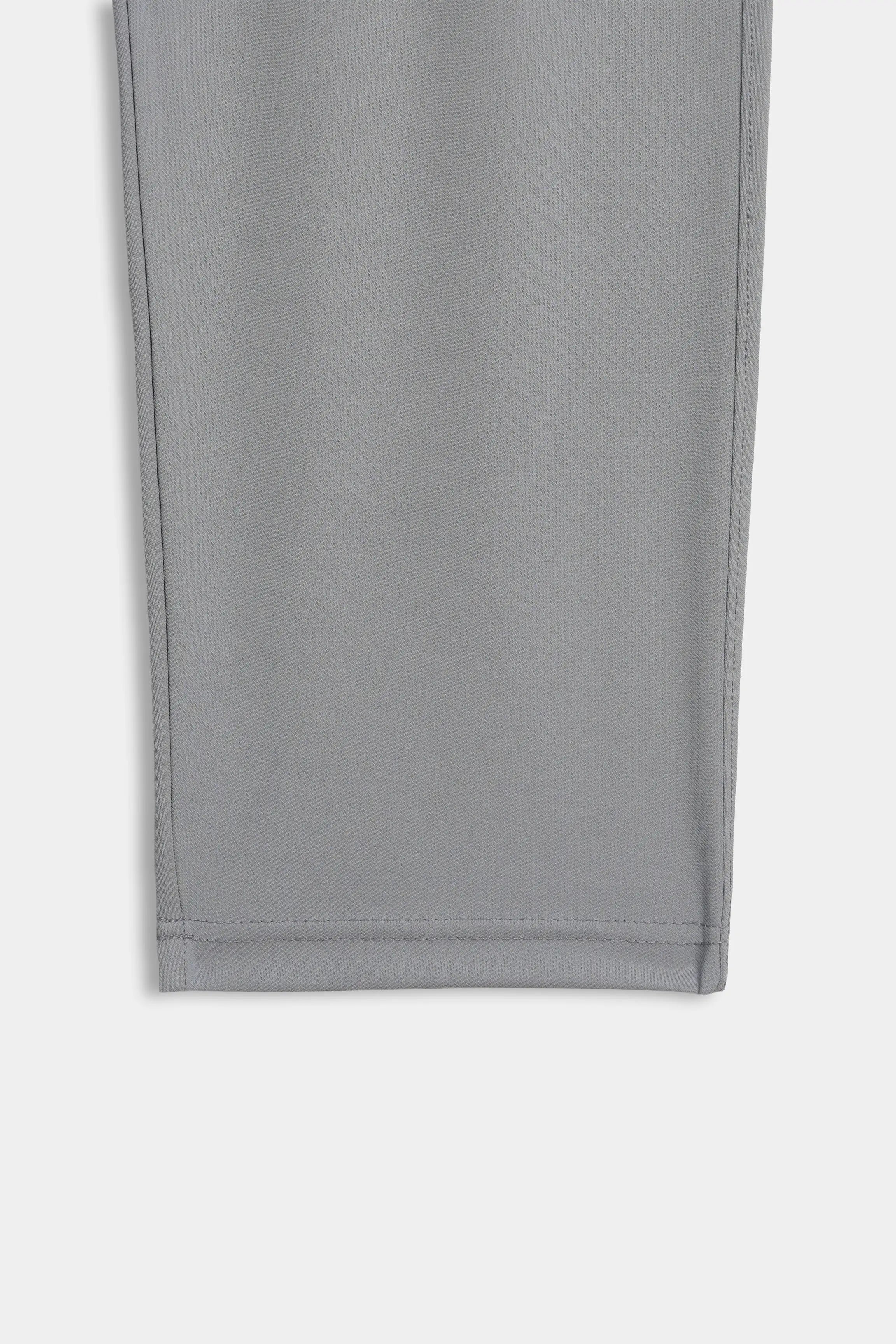 Grey trouser leg fabric panel with visible stitched seam and hem, flat lay detail.