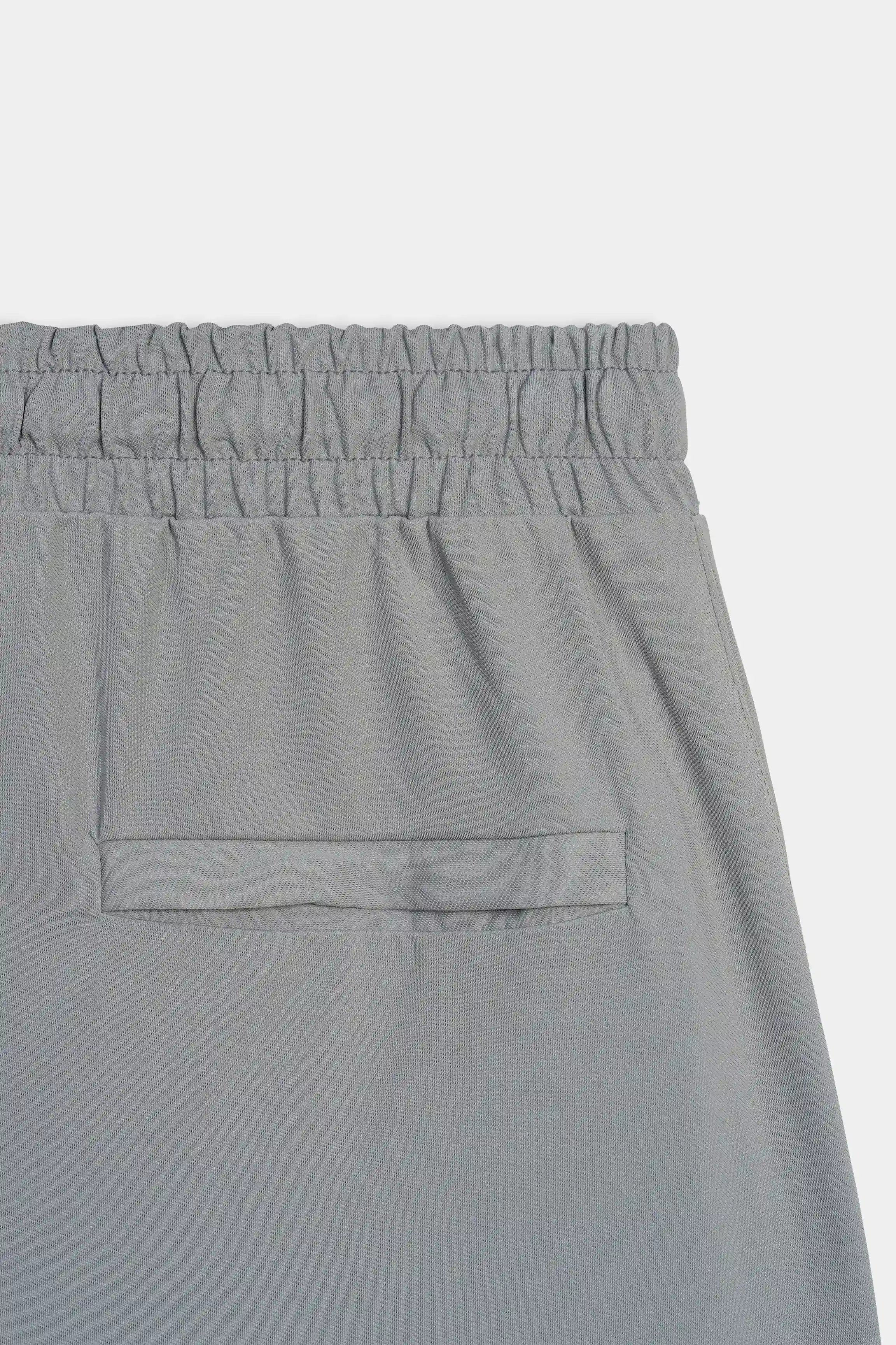 Grey trouser front panel detail with elastic waistband and centered patch pocket.