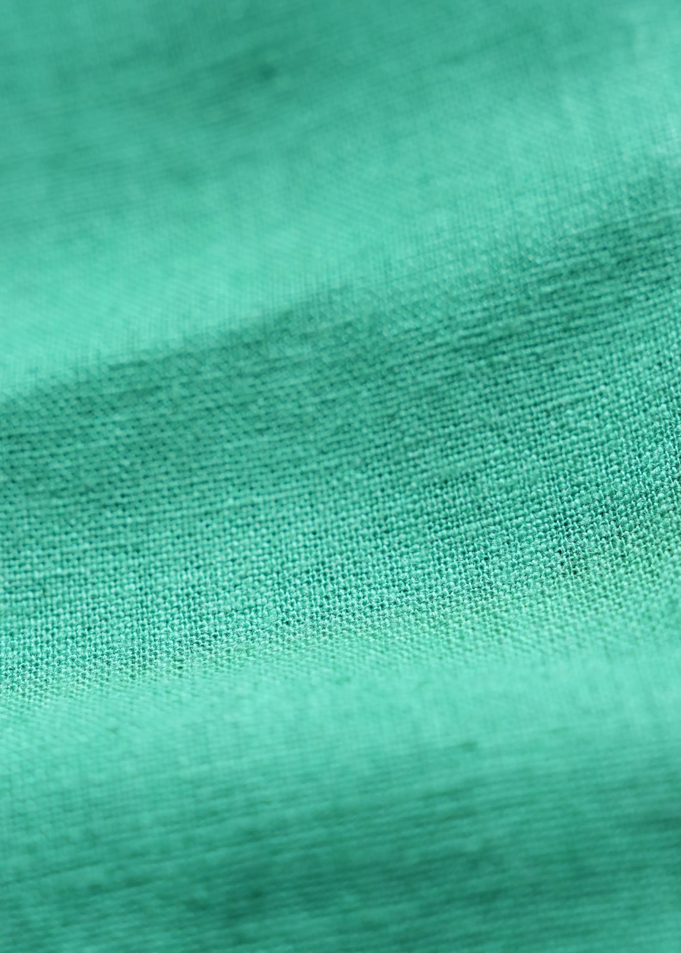 Green linen shirt fabric closeup with fine woven texture