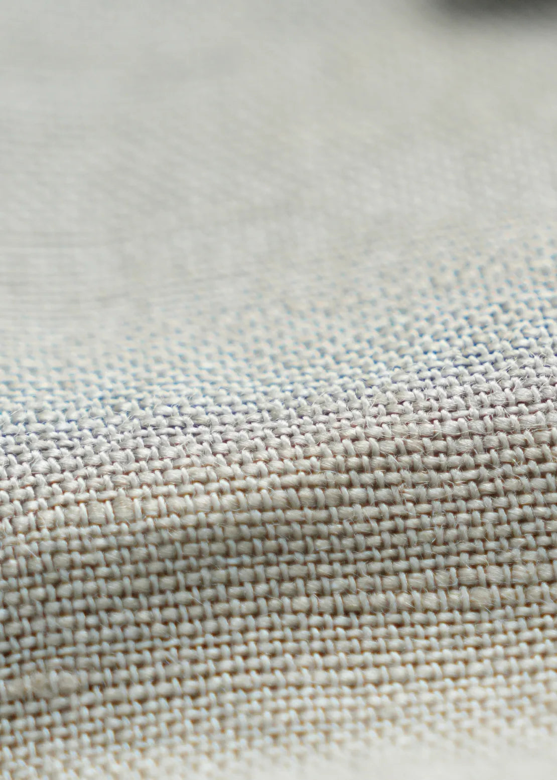 Light olive linen fabric close-up with textured weave and fine stitching