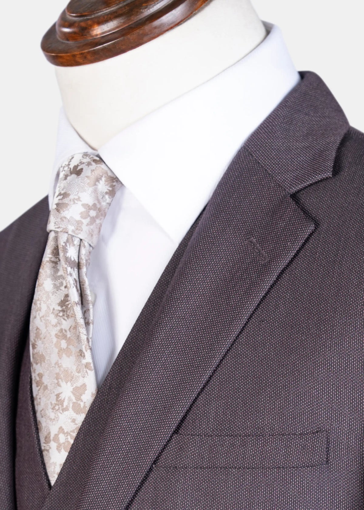 Dark brown suit jacket with notch lapel and flap pocket, paired with patterned tie