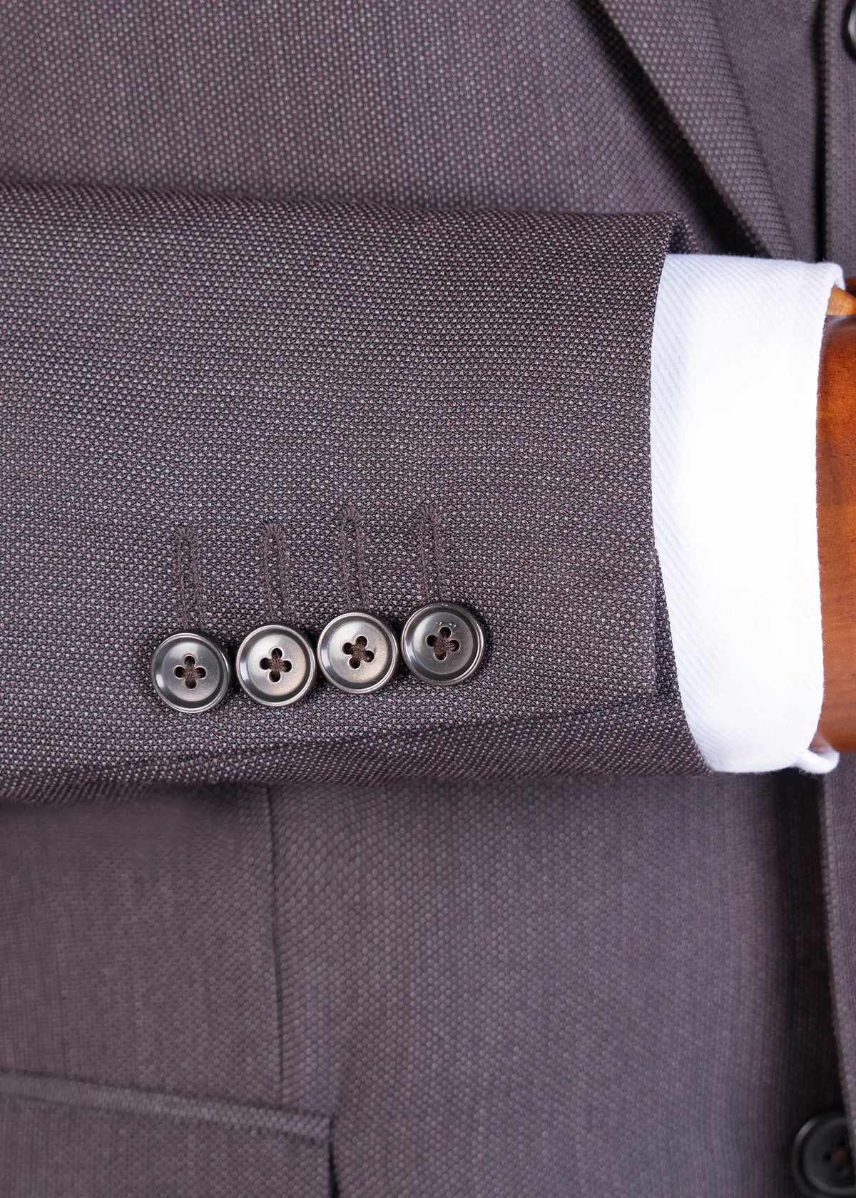 Dark brown suit jacket cuff with four buttons and chest pocket seam detail