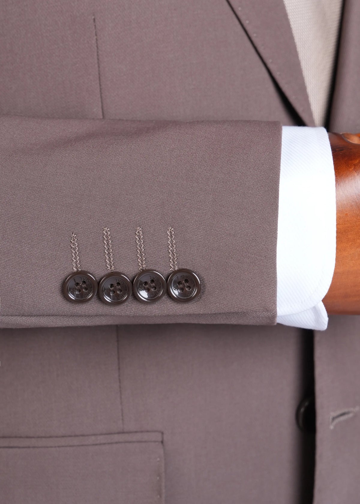 Brown suit jacket cuff and sleeve with four dark buttons on the cuff