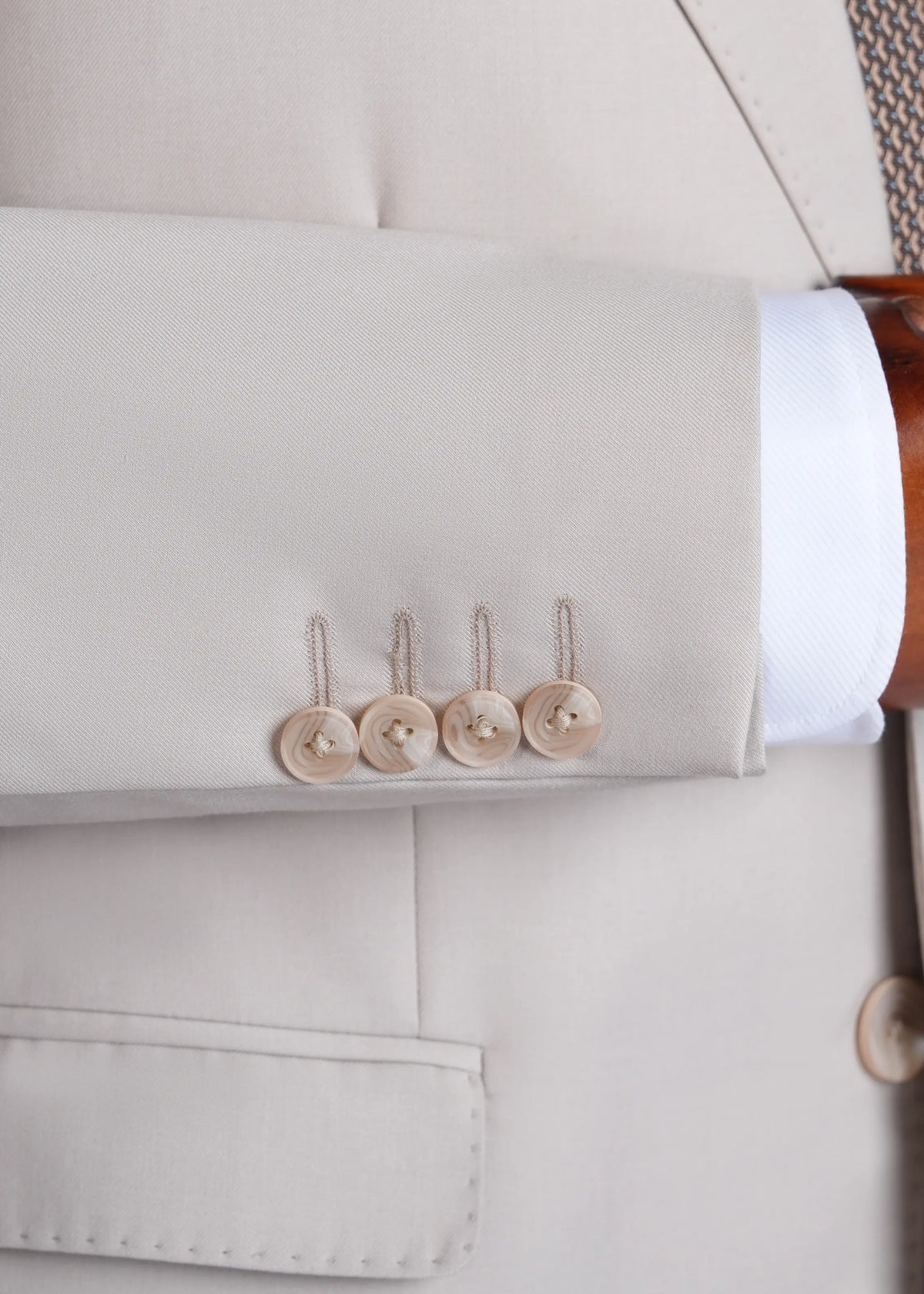 Cream suit jacket cuff and flap pocket with button detail, close-up