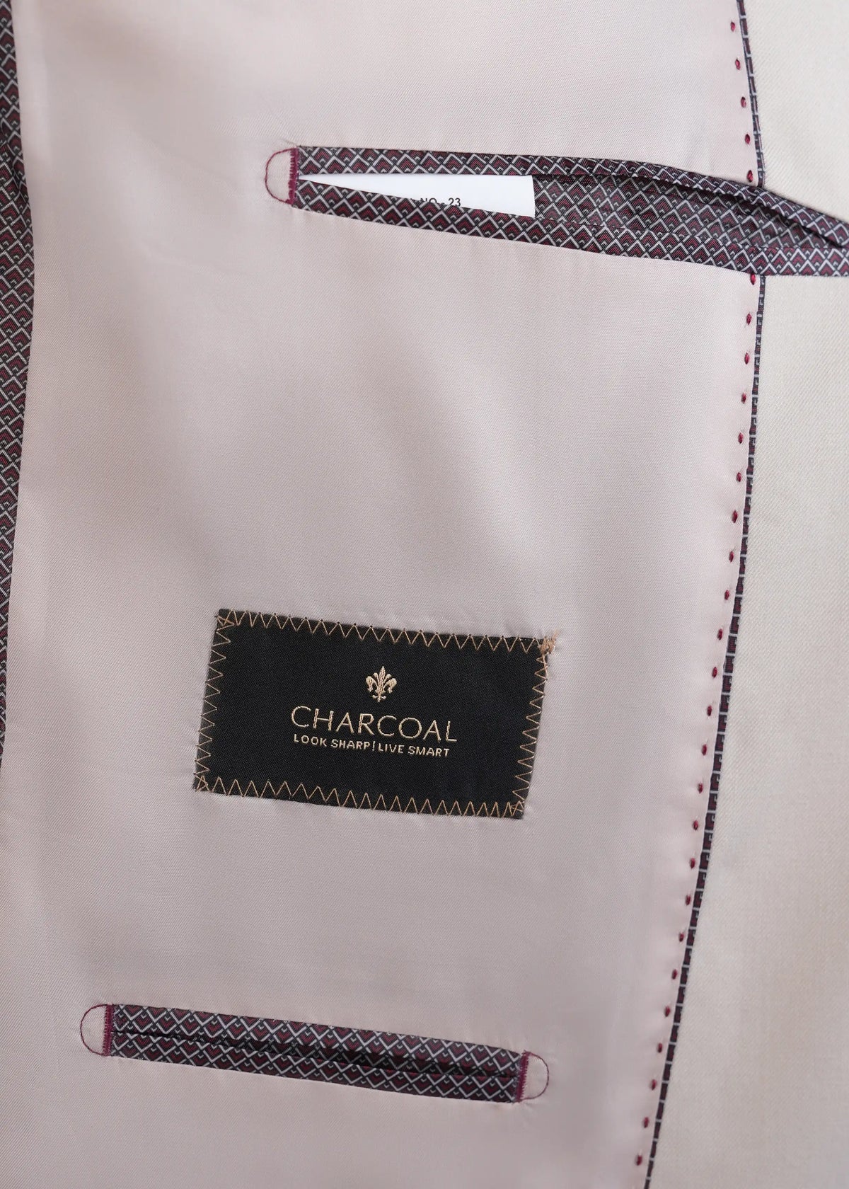 Cream suit jacket lining with 'CHARCOAL' label and stitched trim, close-up