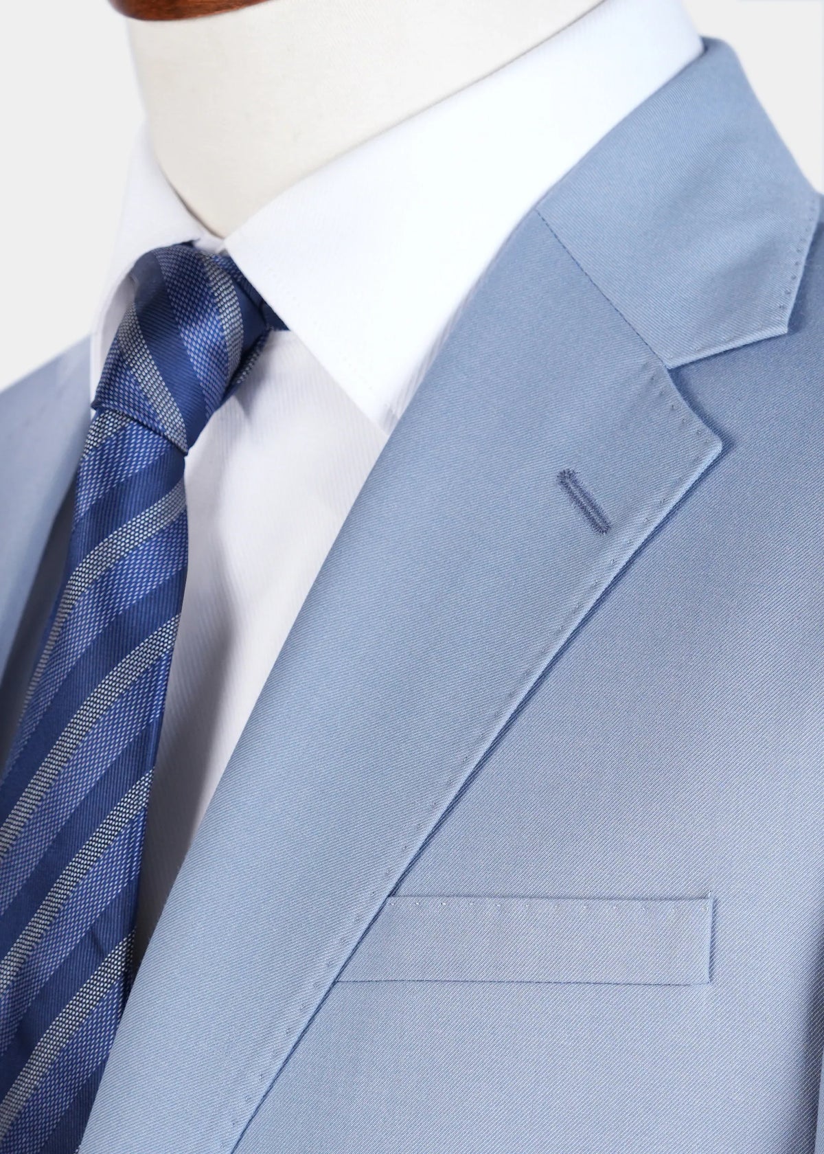 Smoke blue suit jacket lapel detail with single flap pocket and striped tie