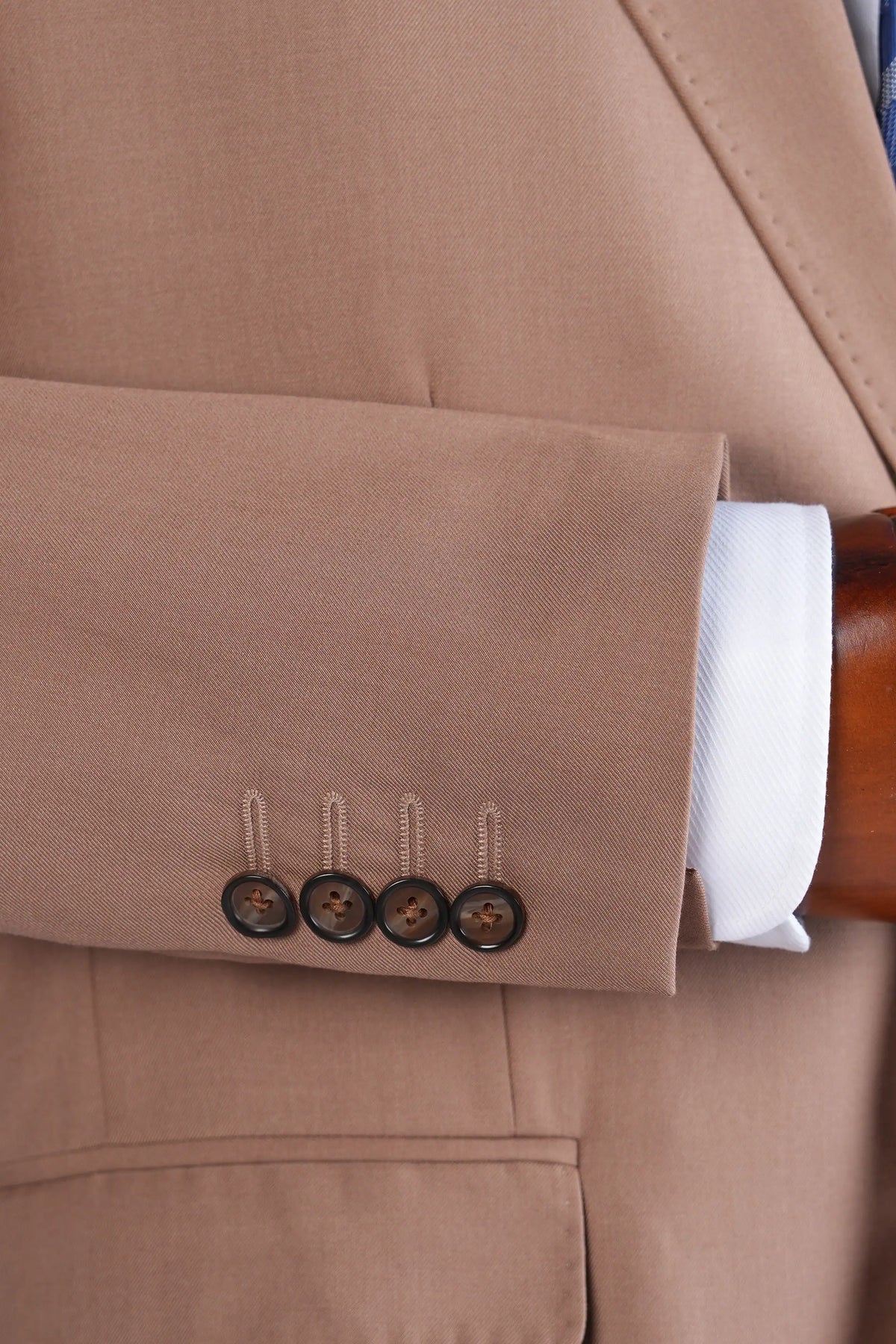 Light brown suit jacket cuff with four-button sleeve and tailored stitching.