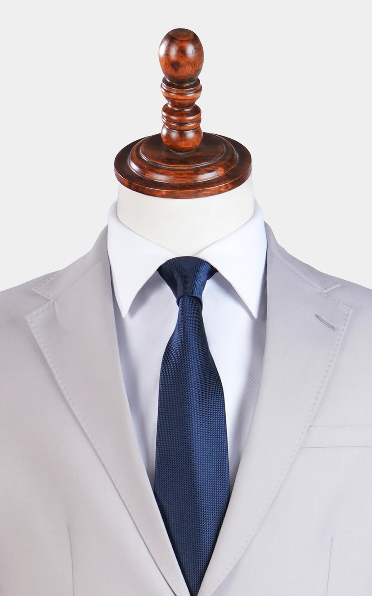 Stone gray notch-lapel suit jacket with navy textured tie and white shirt