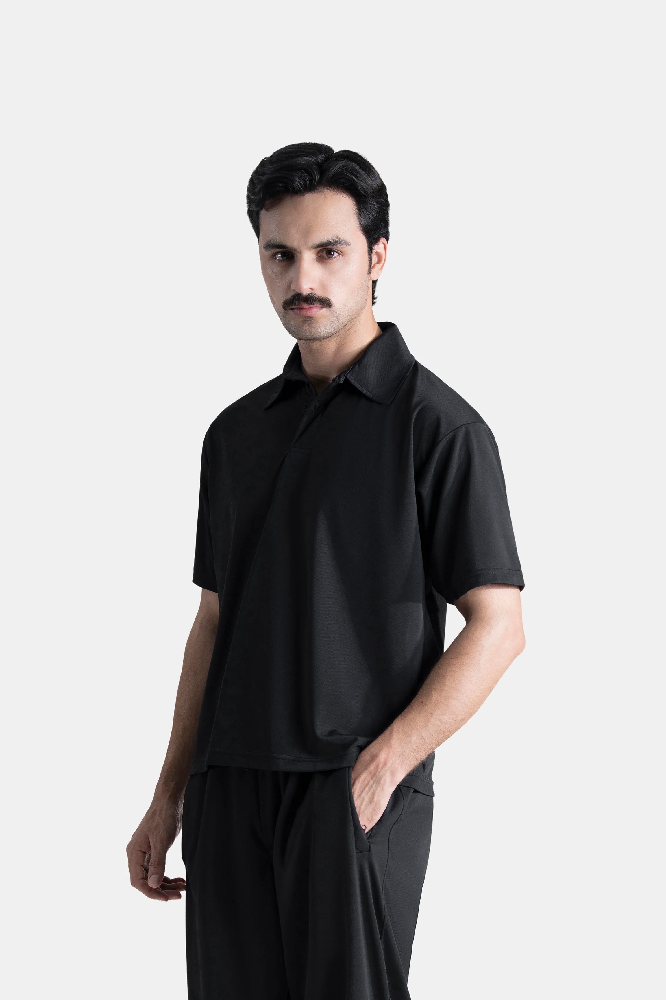 Black polo shirt with short sleeves, spread collar, and loose fit