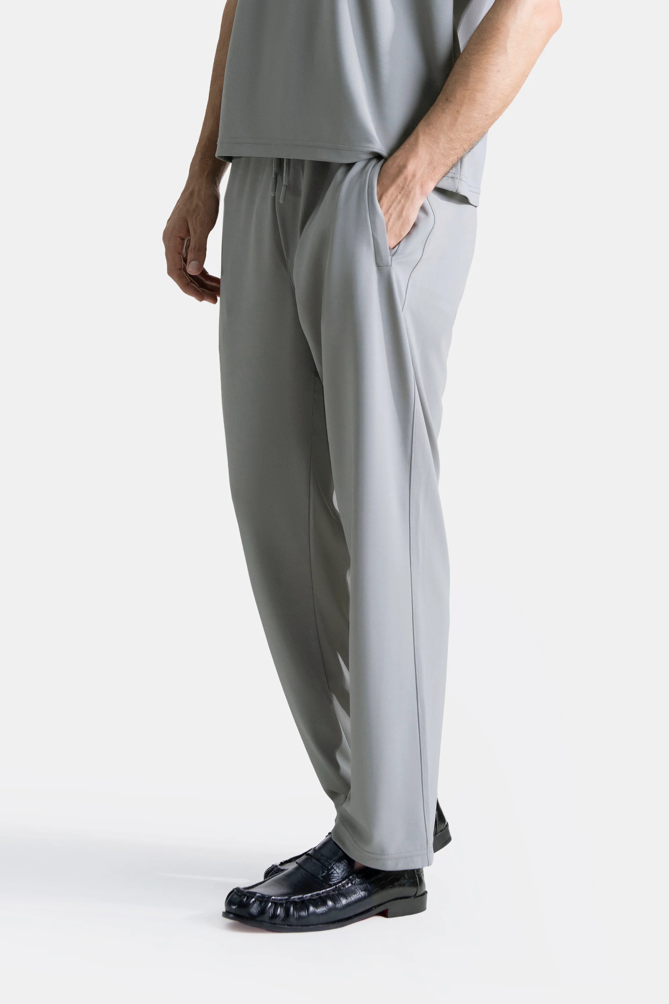 Grey loose-fit trousers, elasticated waist, side view with straight wide legs.