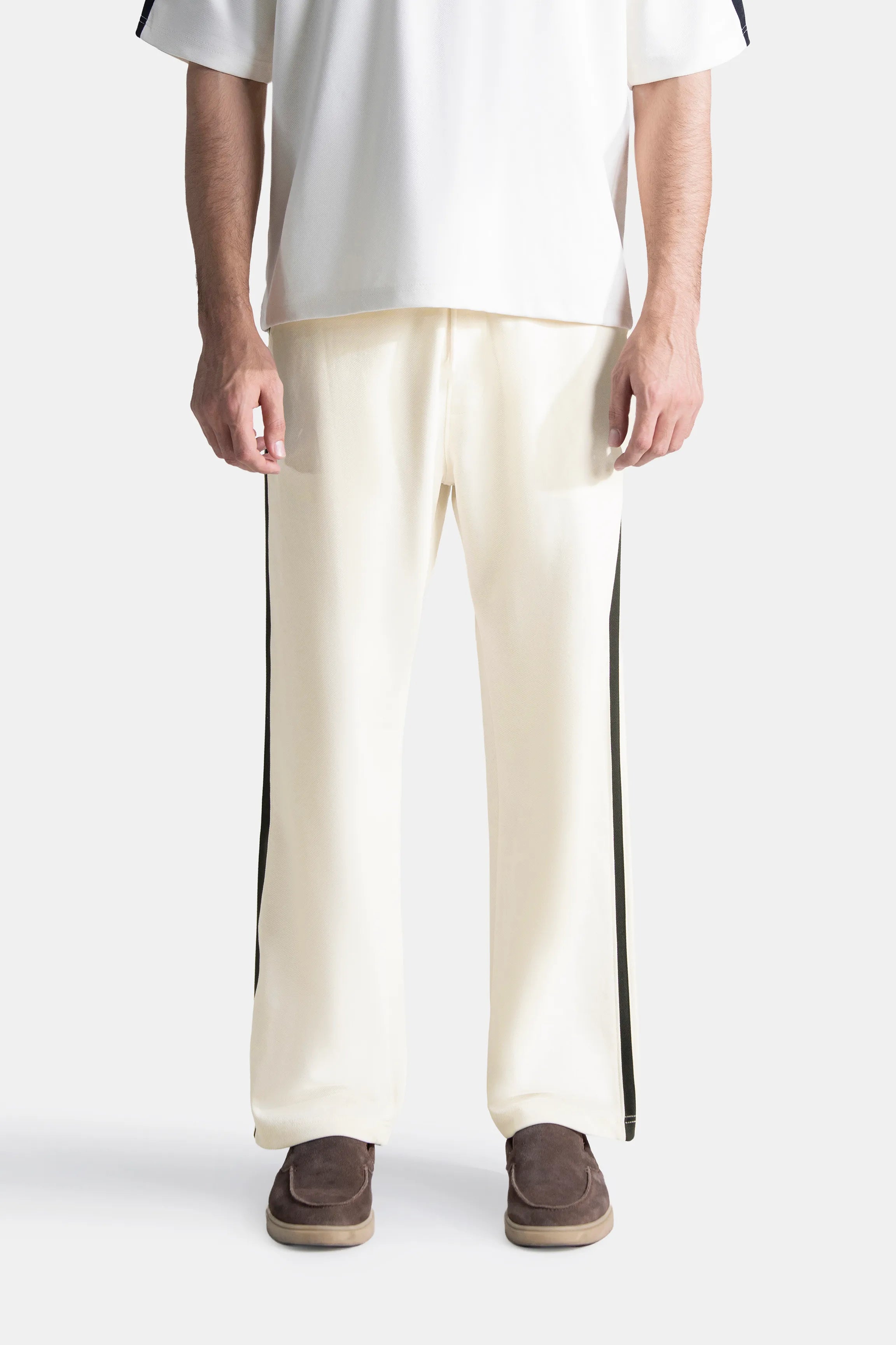 Off-white loose-fit trousers with black side stripe, drawstring waistband