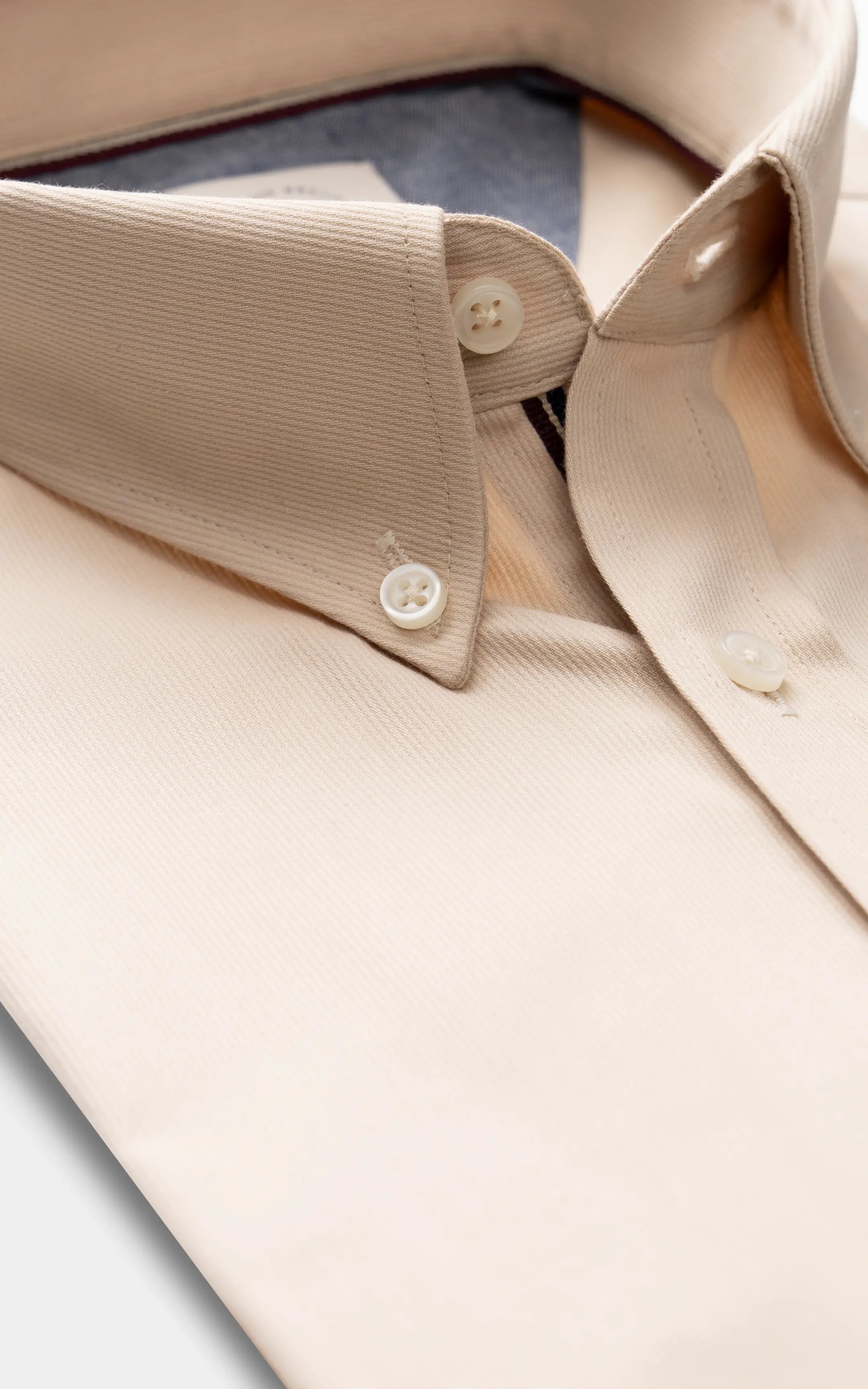 Khaki button-down shirt collar close-up with white buttons