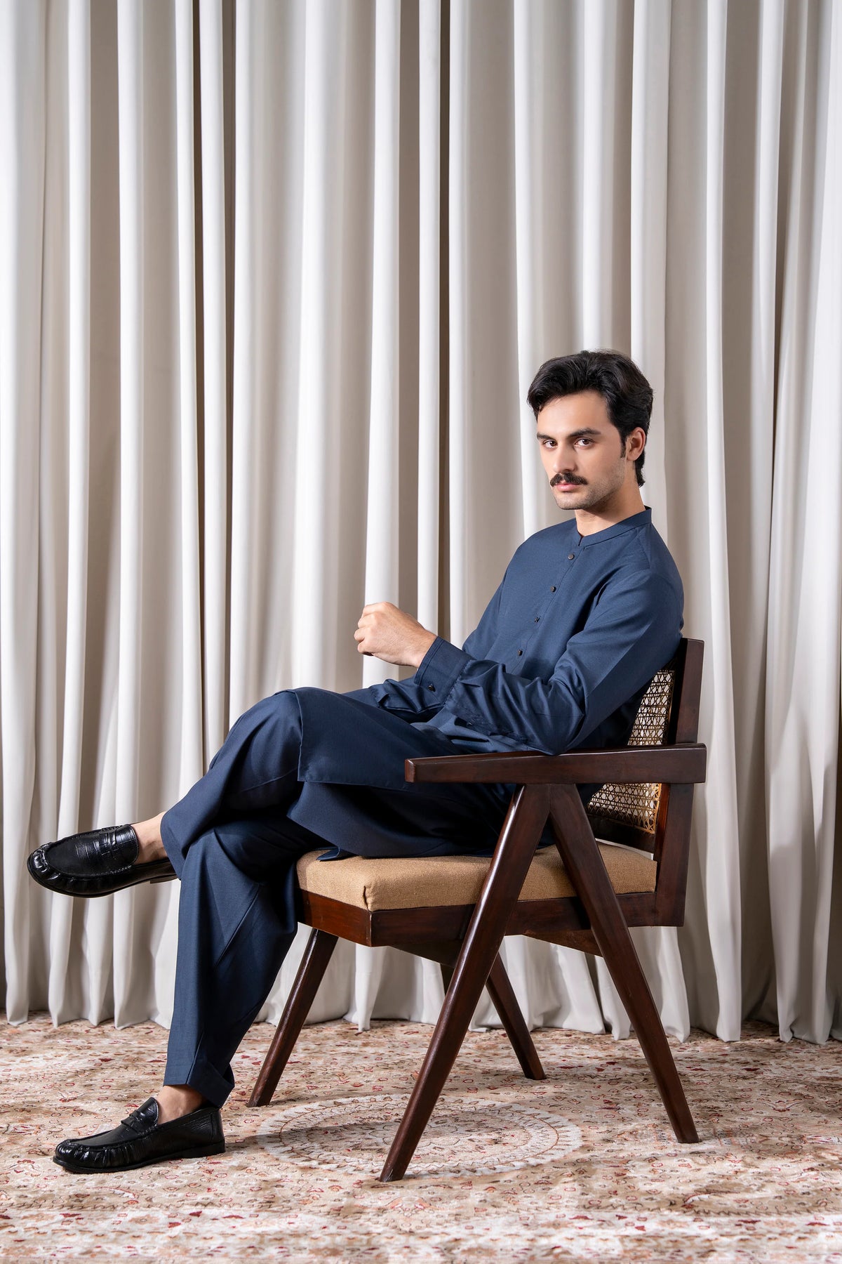 Indigo kameez and shalwar set, seated pose showing full length
