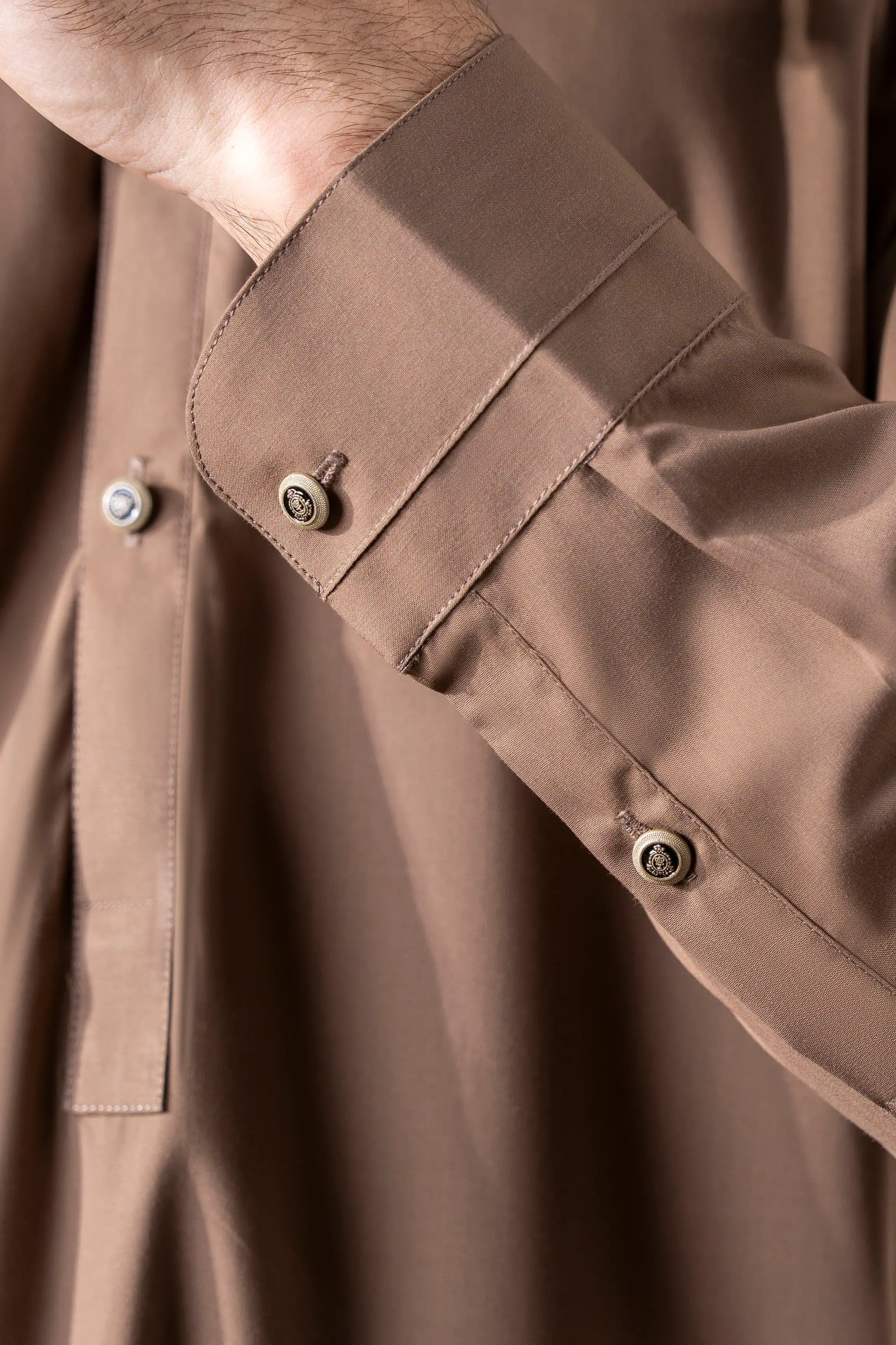 Close-up of dark khaki kameez collar and cuffs with round button and placket