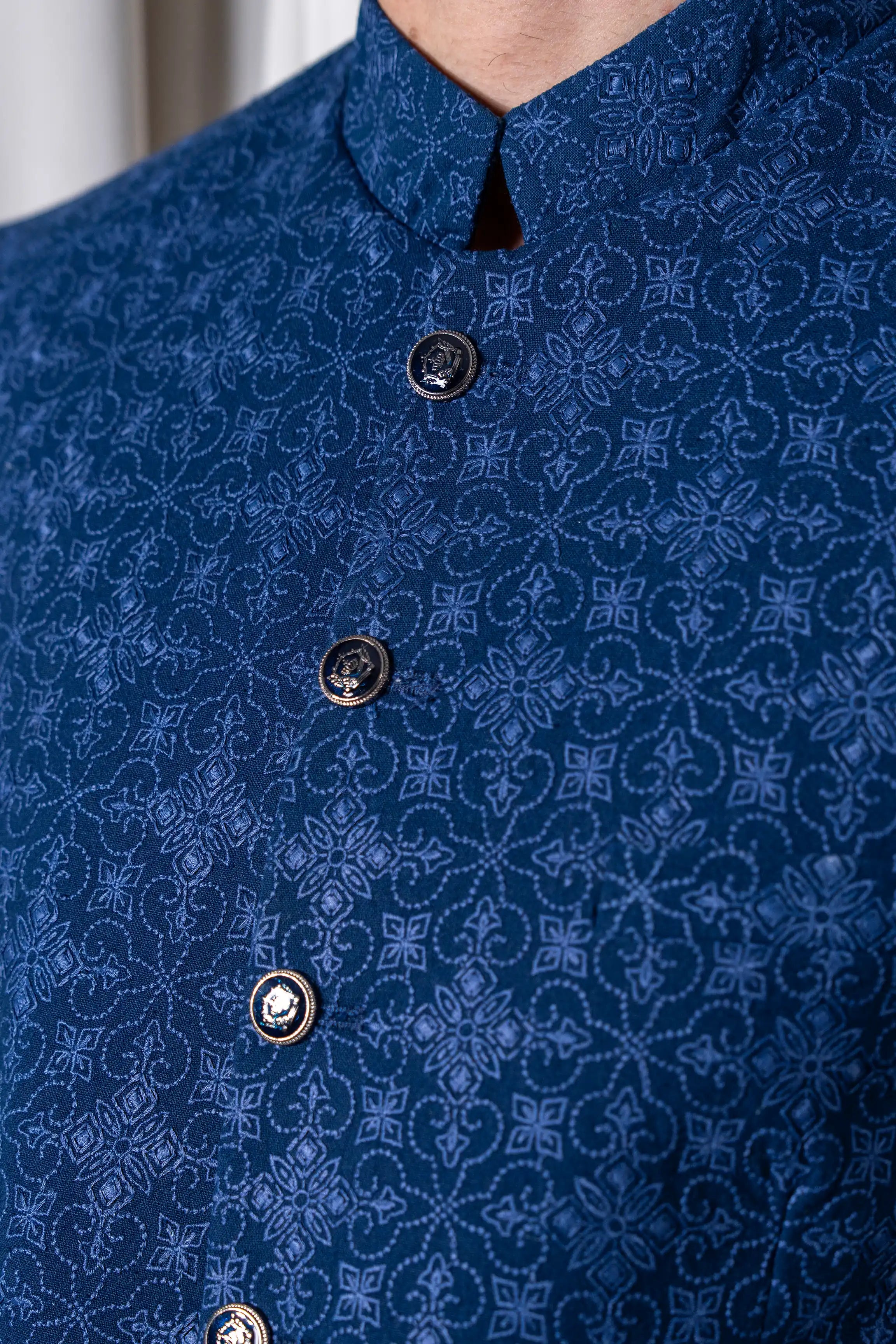 Close-up of blue embroidered coat with dark round button front