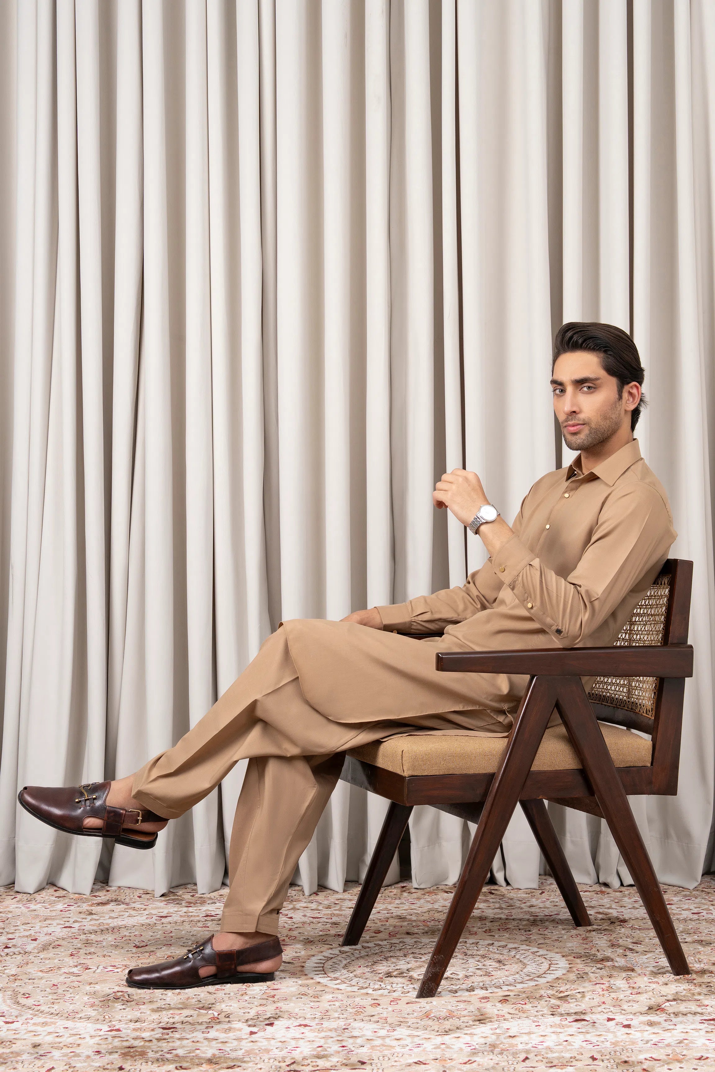 Khaki kameez shalwar set with long tunic and tapered shalwar, shown seated