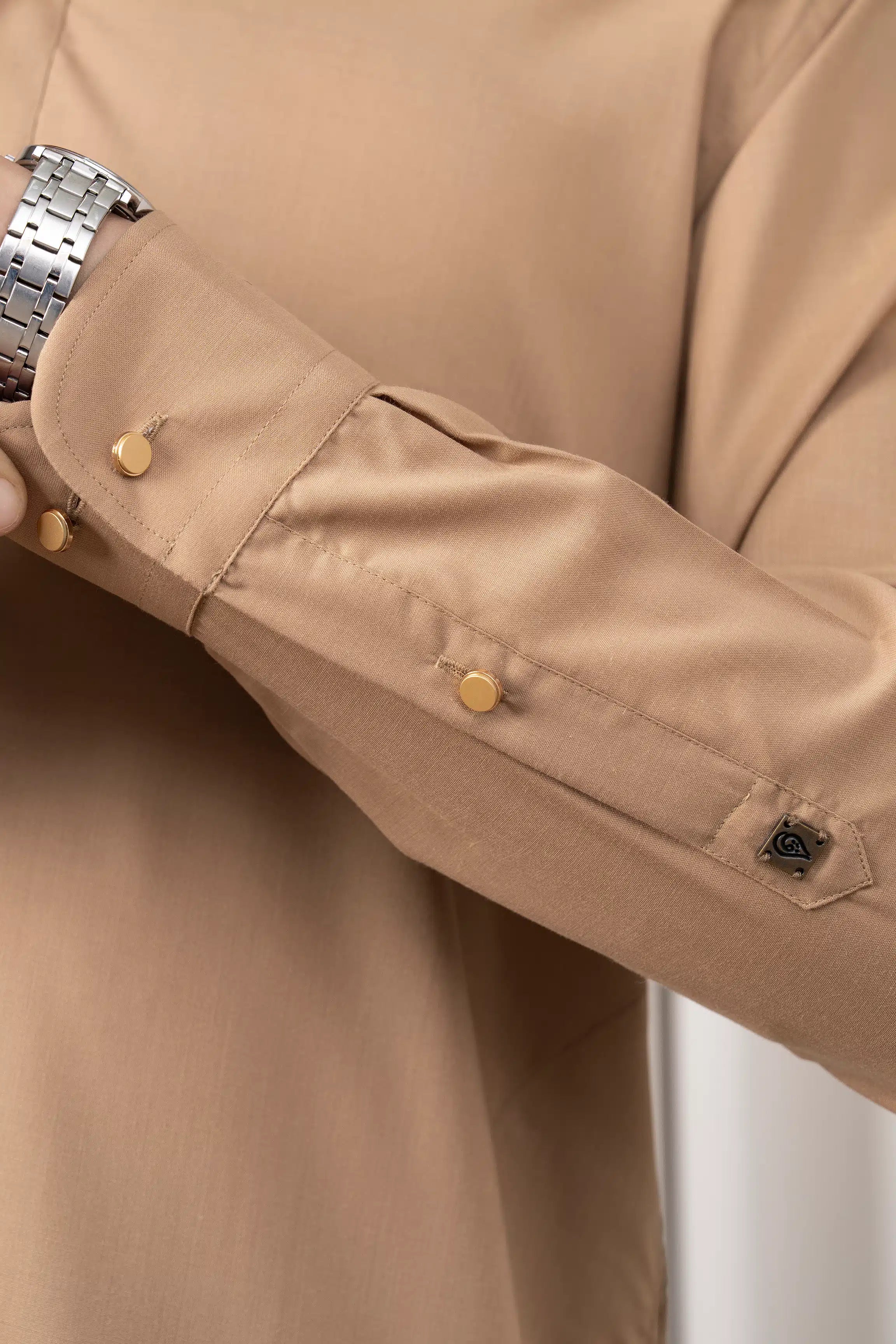 Khaki kameez sleeve cuff with buttoned tab and small embroidered badge