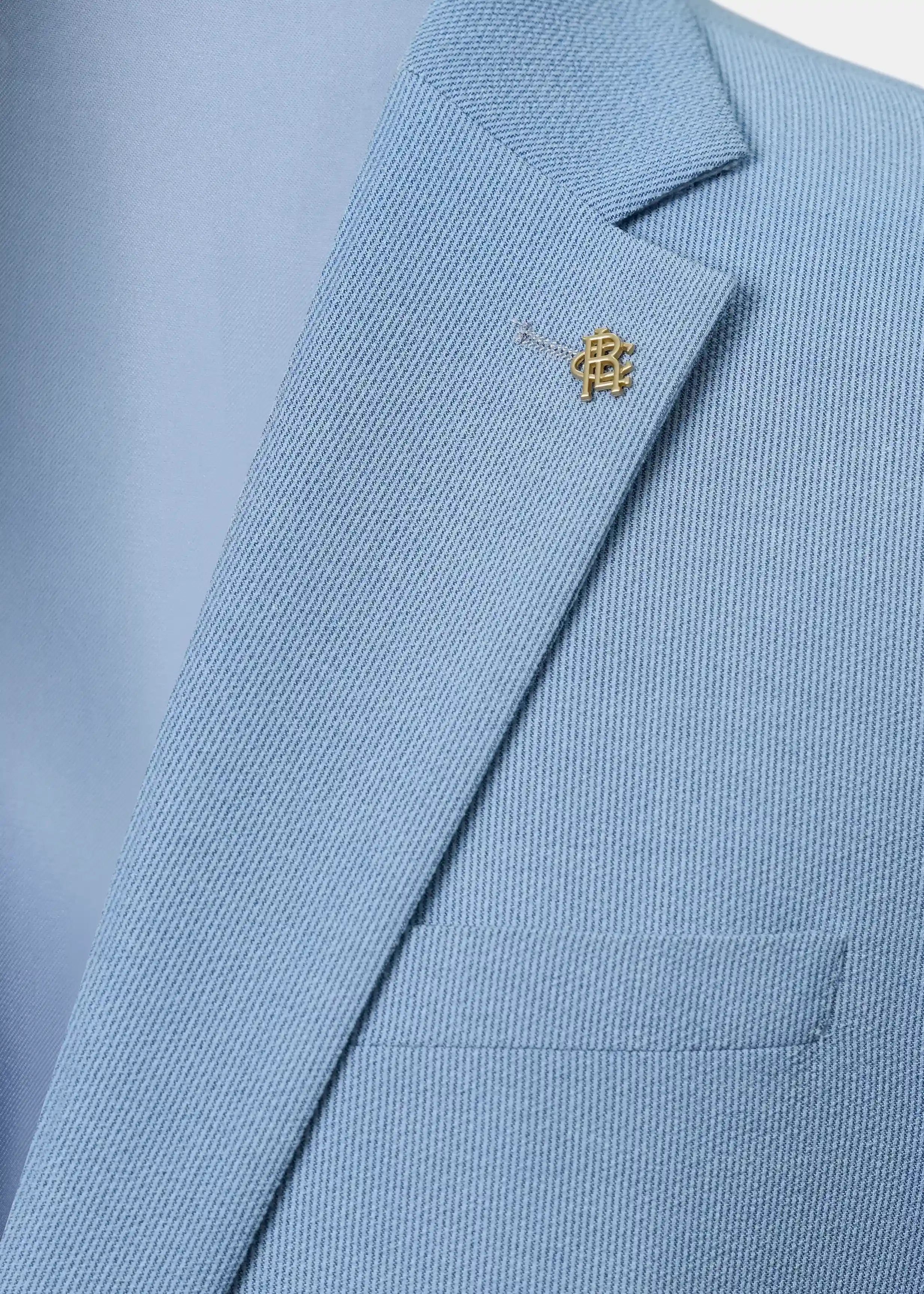 Sky blue coat lapel with small decorative pin and angled collar seam