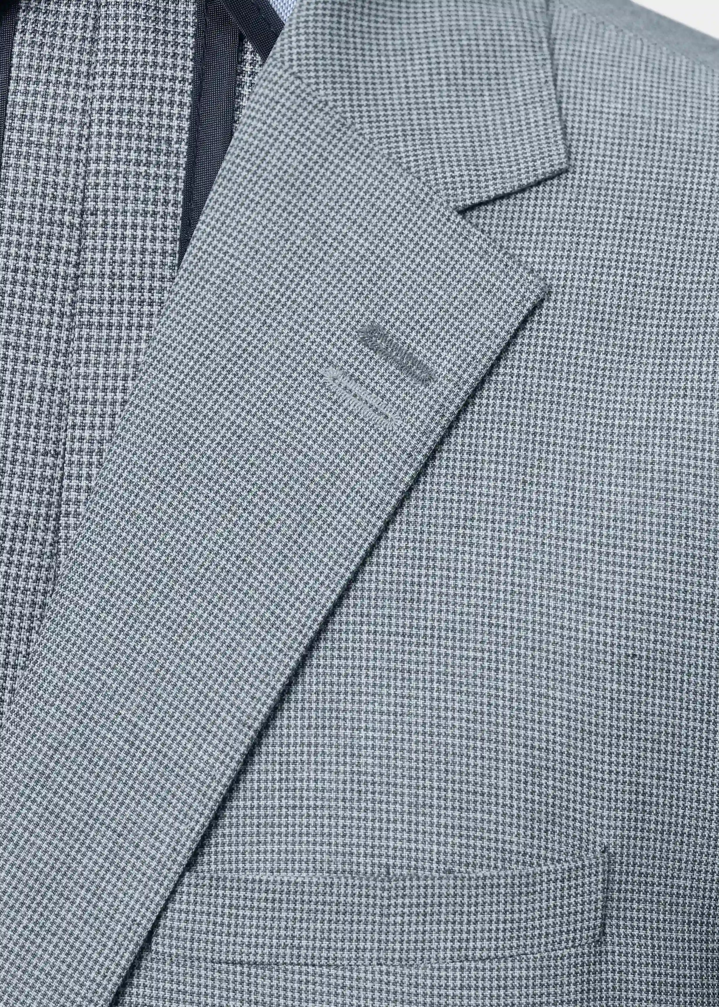 Grey houndstooth check fabric close-up on casual coat lapel and chest area