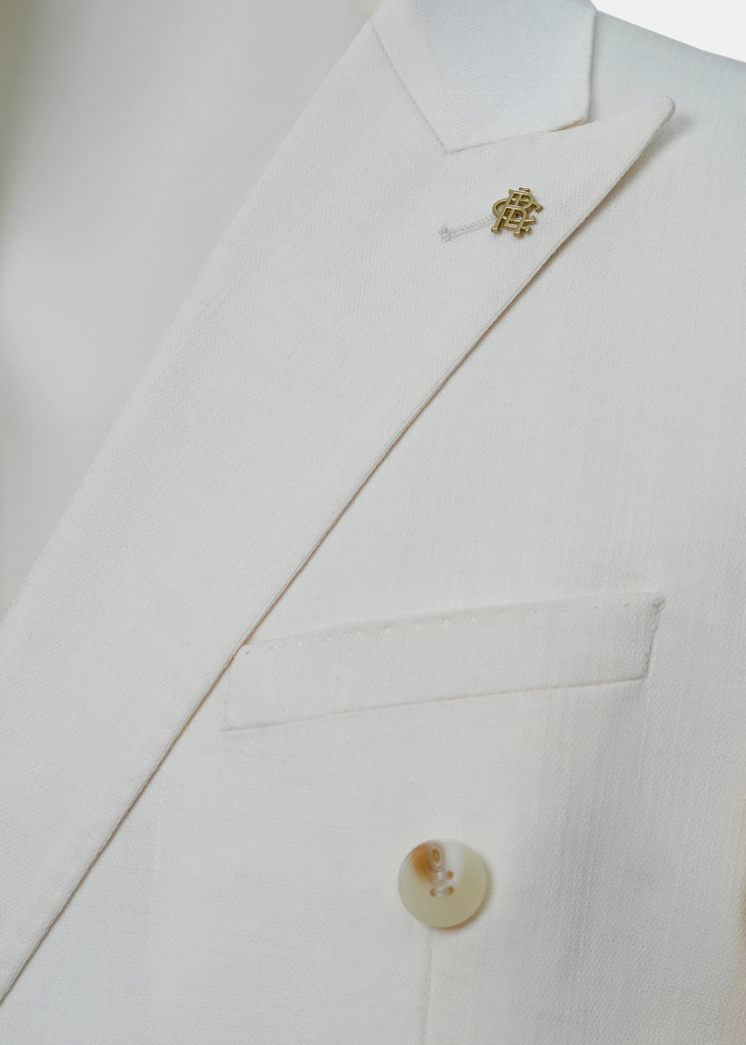 Off-white coat collar with gold-toned emblem pin and button detail