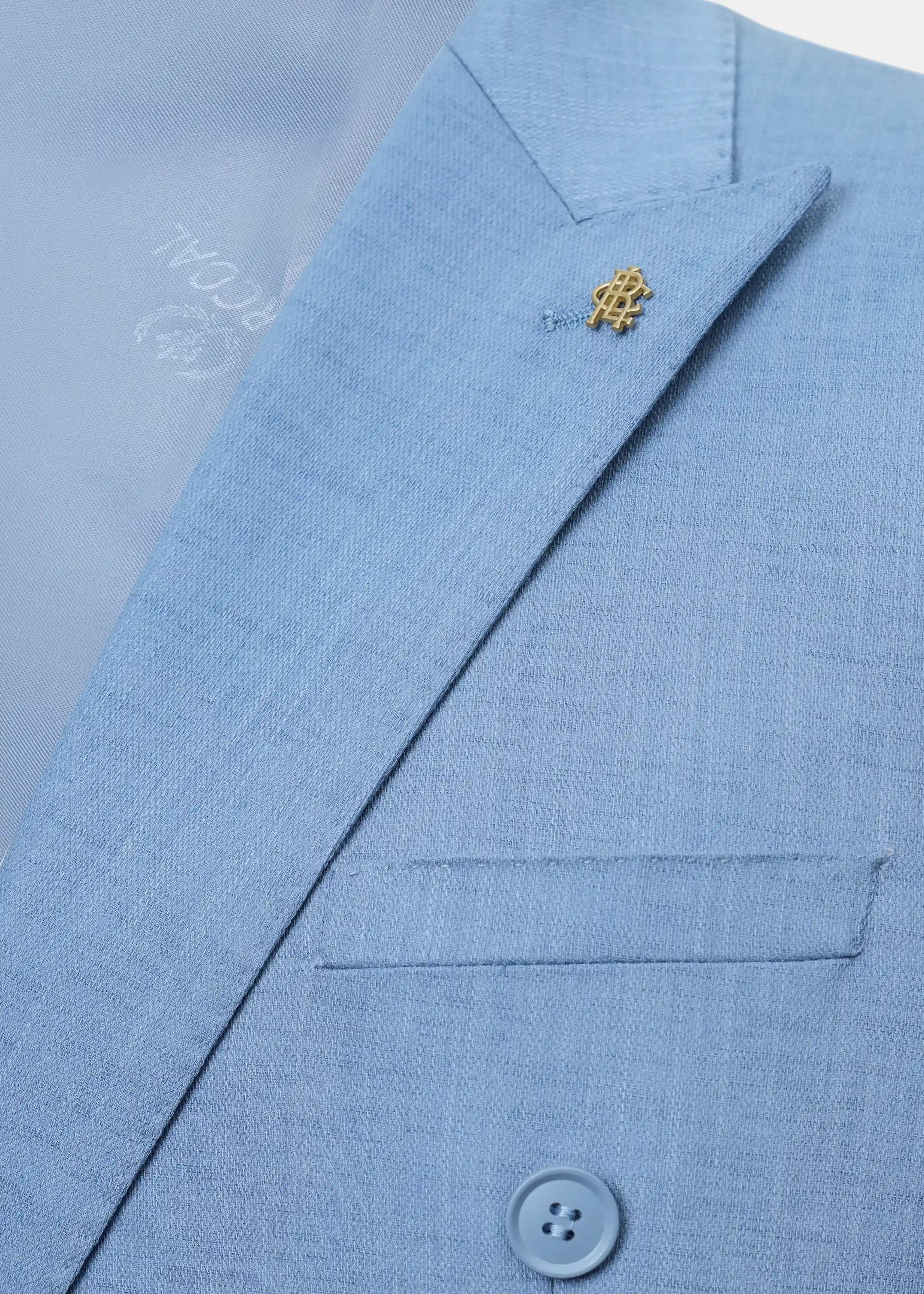 Light blue coat lapel with pocket flap detail and gold-tone emblem