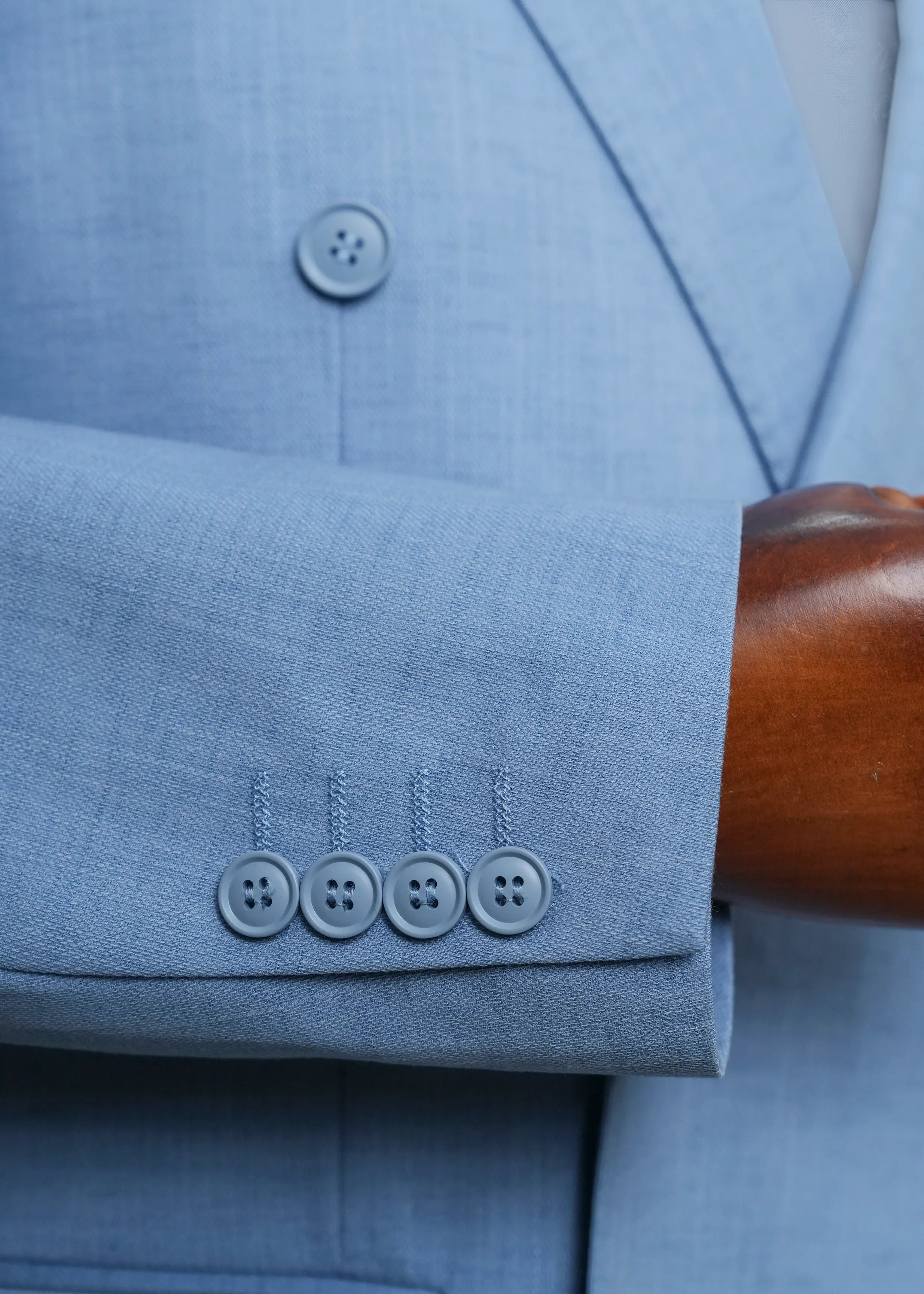 Light blue coat sleeve cuff with four-button detail and welt pocket seam