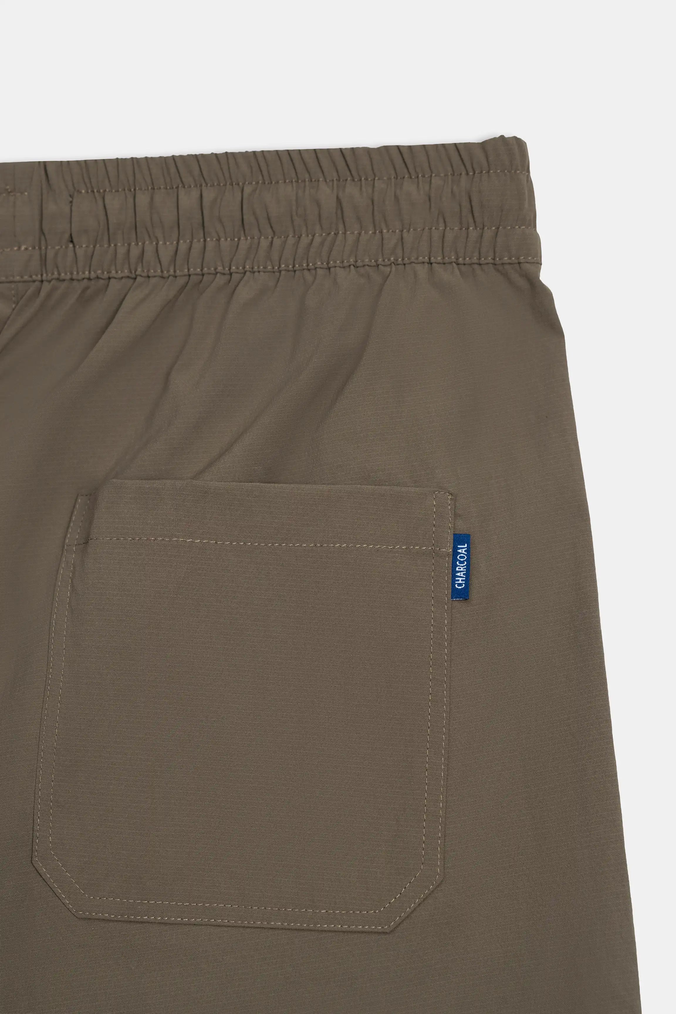 Olive trouser side pocket with stitched detail and small label on the pocket