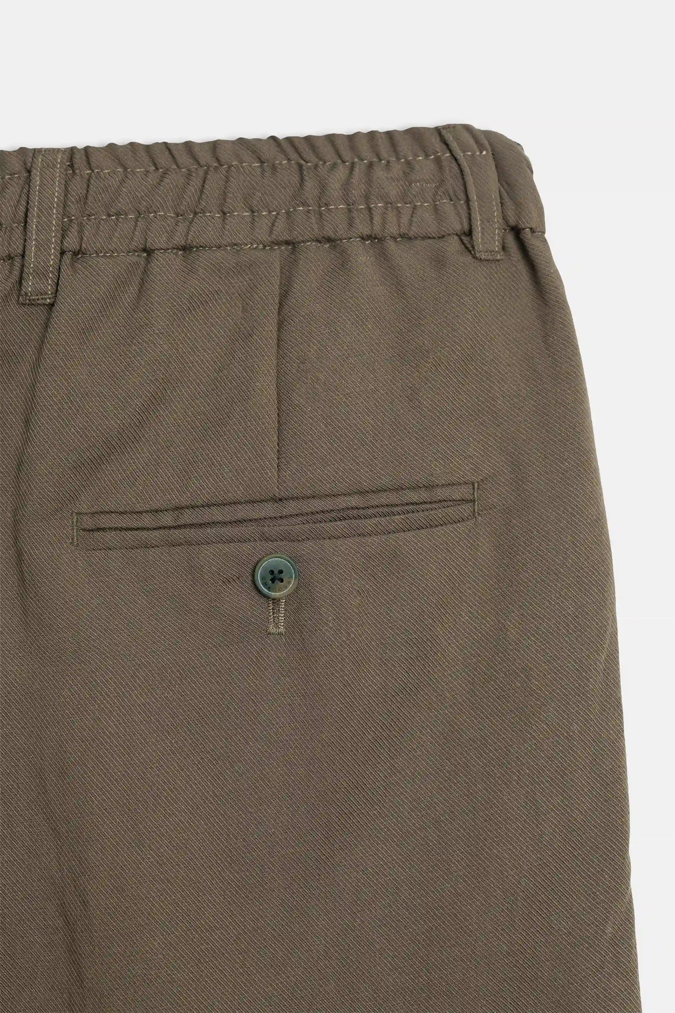 Brown pants waistband detail with buttoned pocket and elastic back