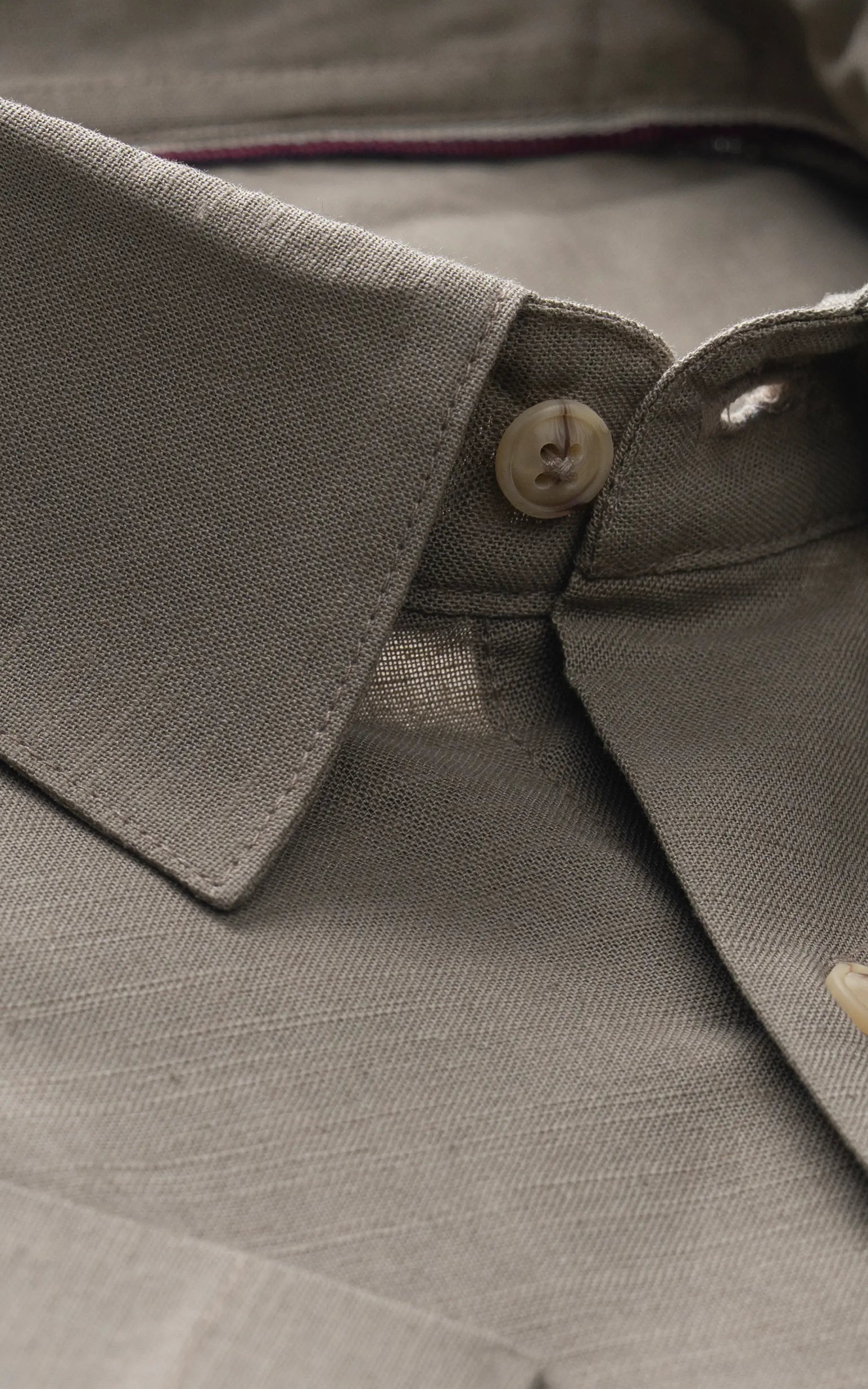 Light olive button-up shirt collar with two tan buttons and placket