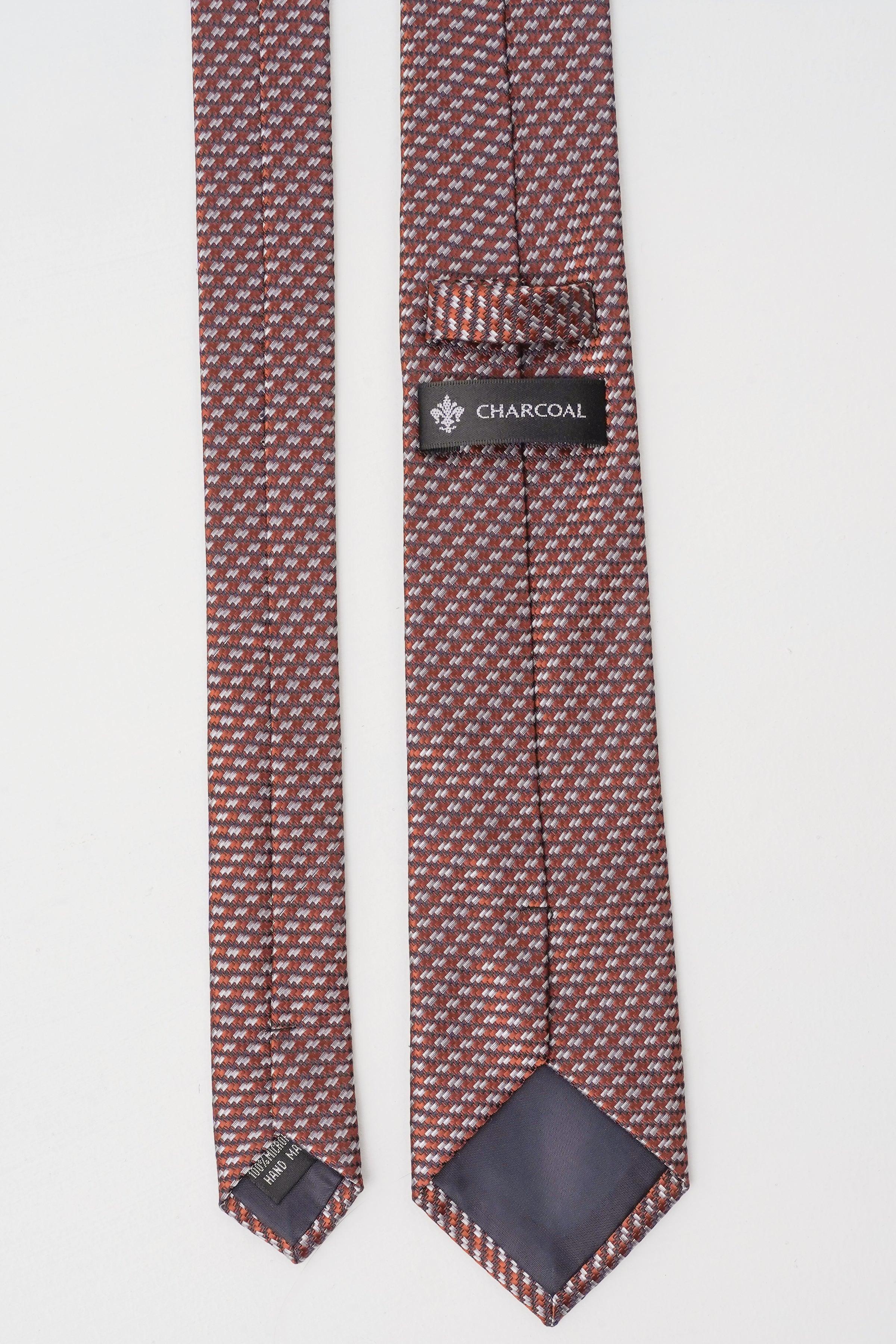Maroon silk tie with geometric weave, 'CHARCOAL' tag near back keeper, pointed tips.