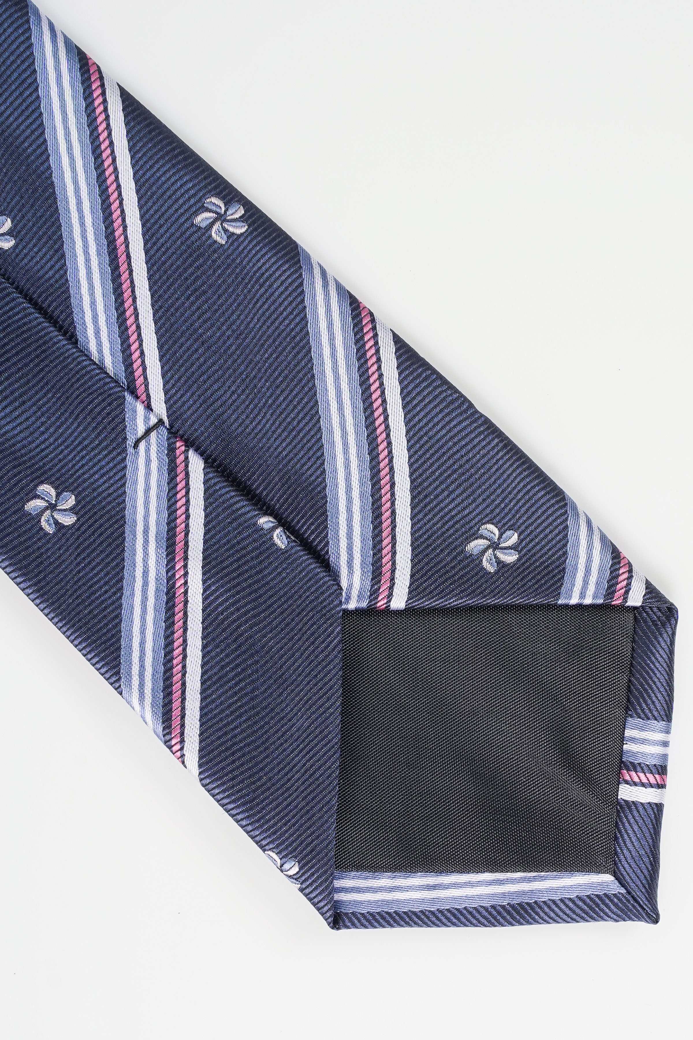 Navy necktie showing striped interior lining and clover pattern at the end