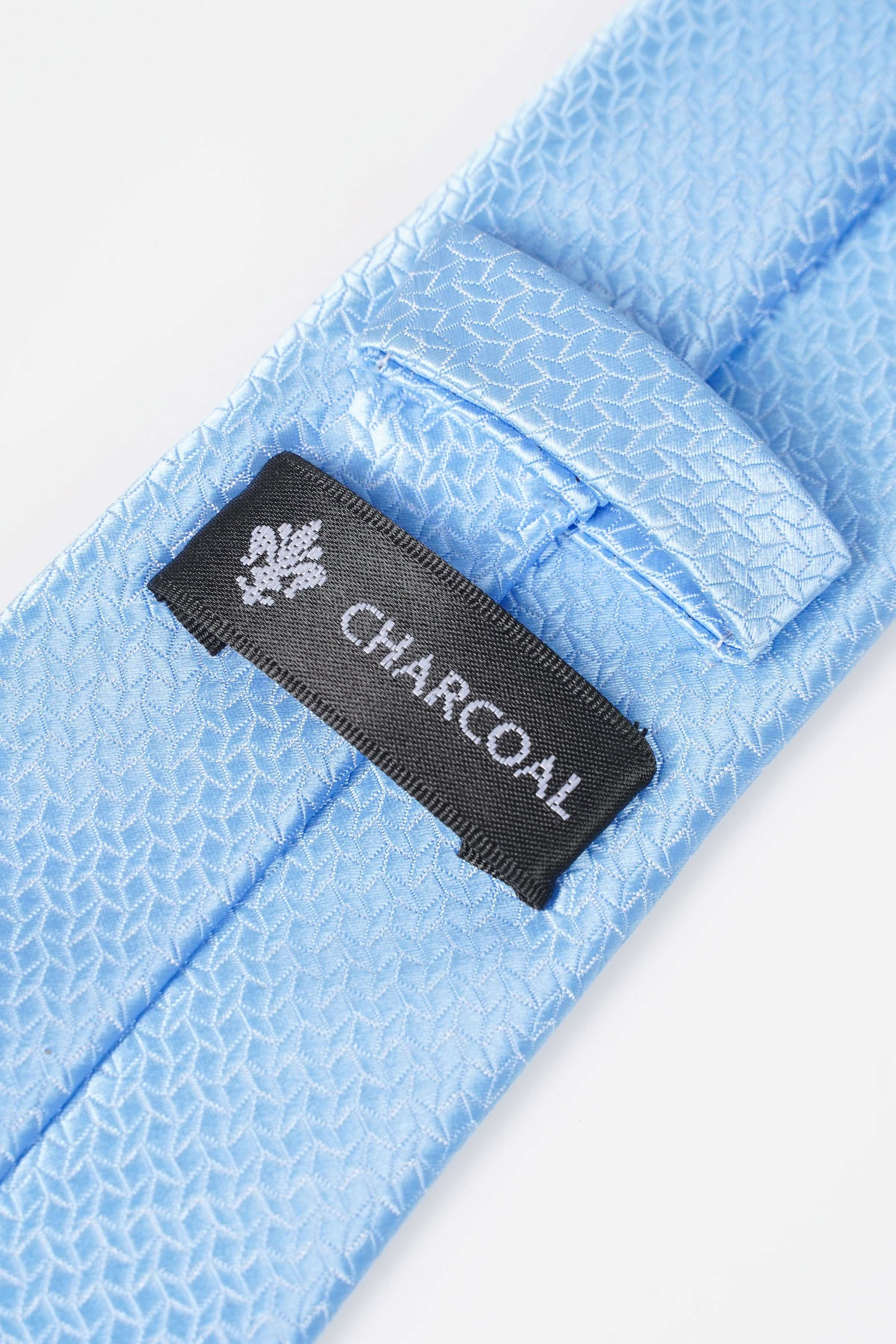 Light blue tie with charcoal brand label and white emblem