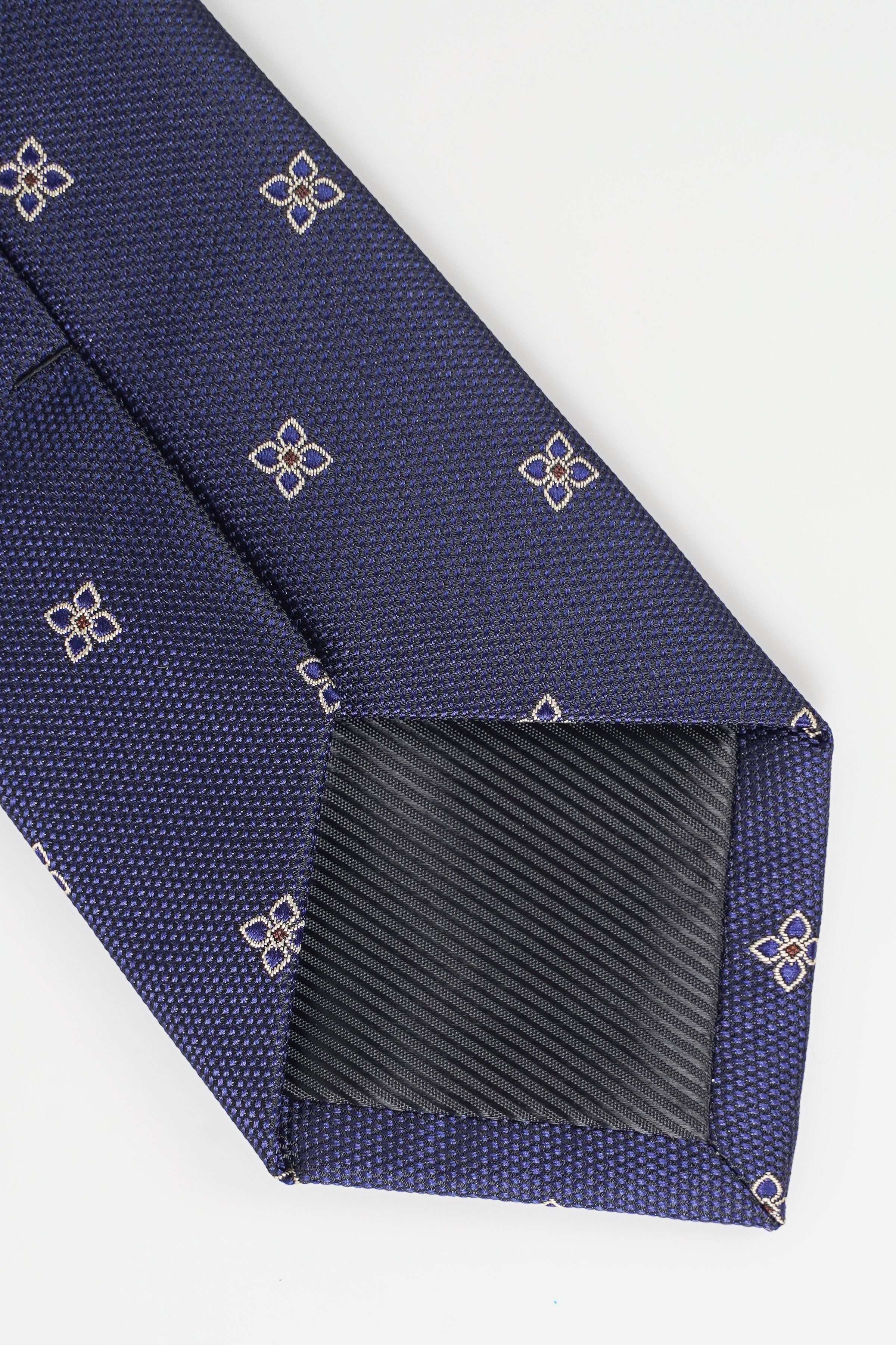 Dark blue necktie tip with gold geometric motifs and visible woven texture