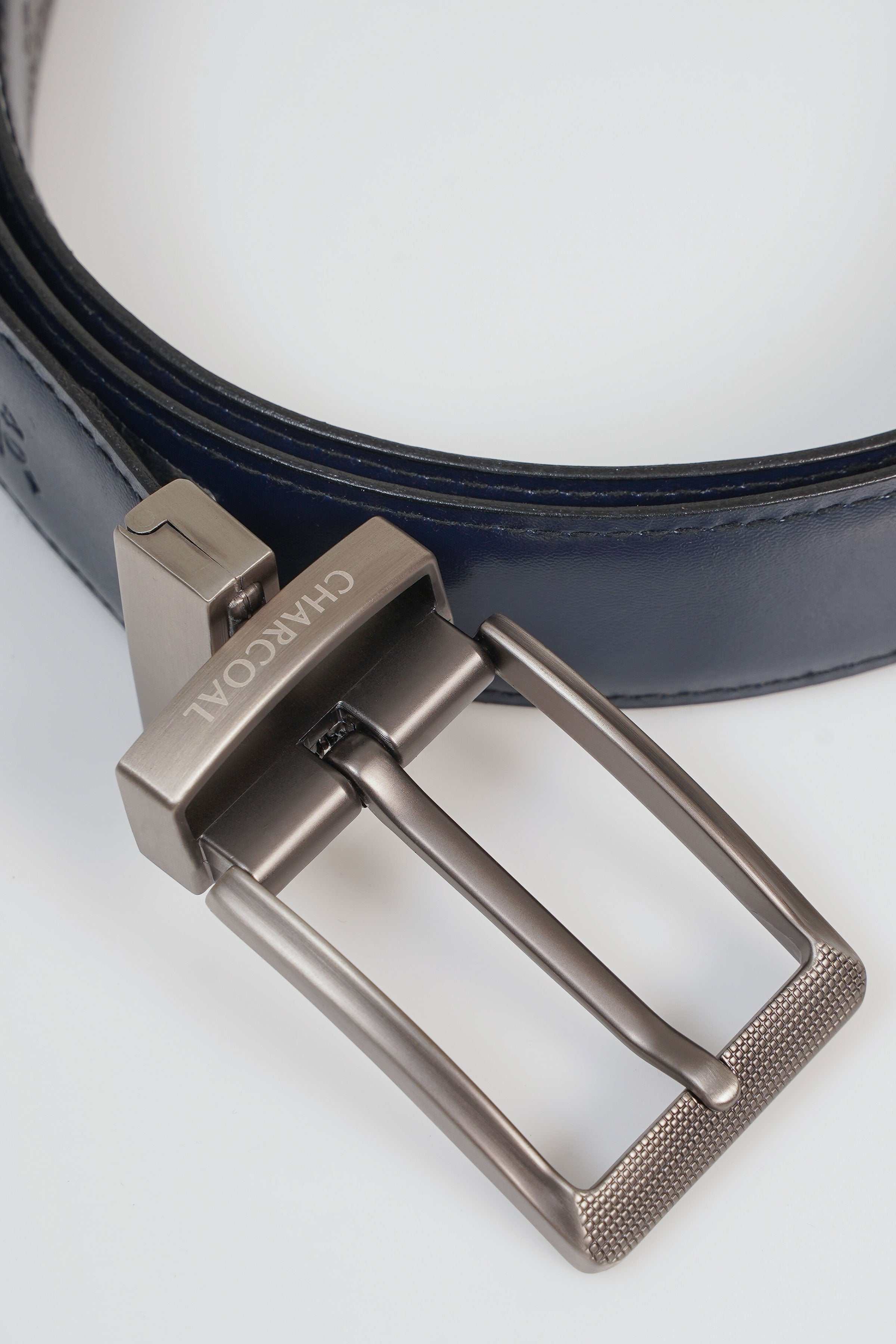 Reversible belt buckle detail with silver frame on dark navy strap