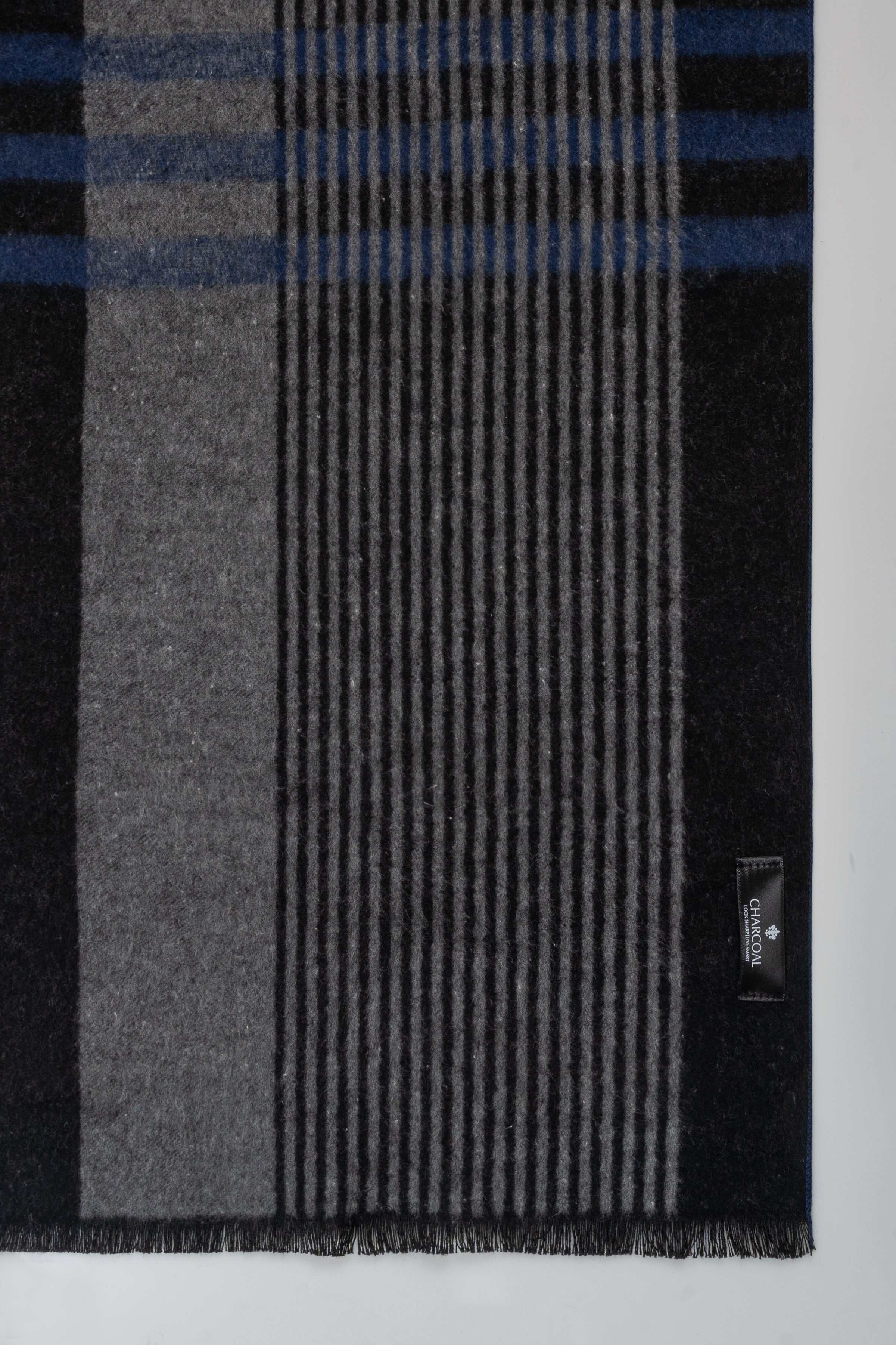 Woven plaid scarf in dark gray with blue stripes and ribbed texture, with hem.