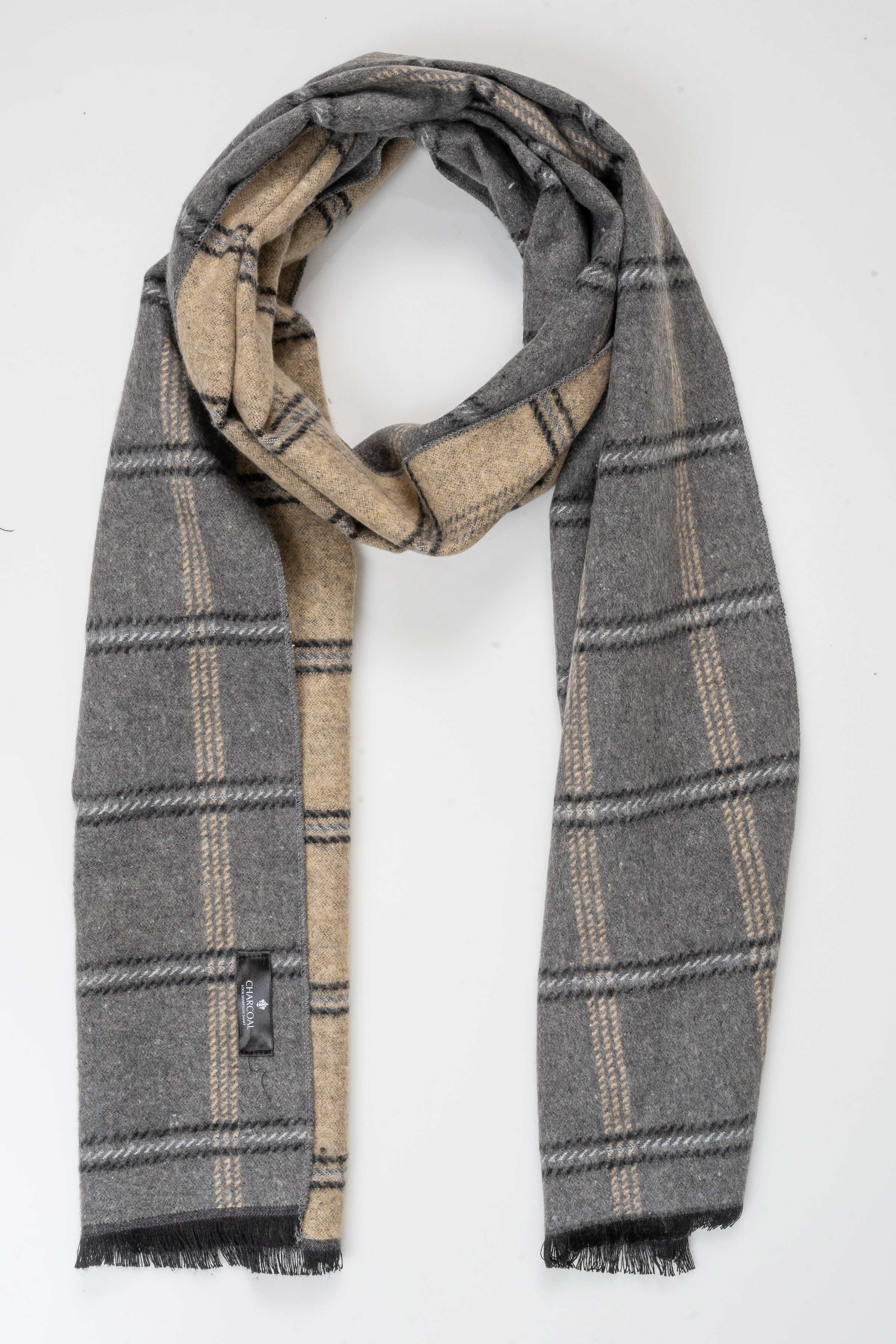Plaid scarf draped in a loop, dark gray with tan and cream accents, fringed ends.