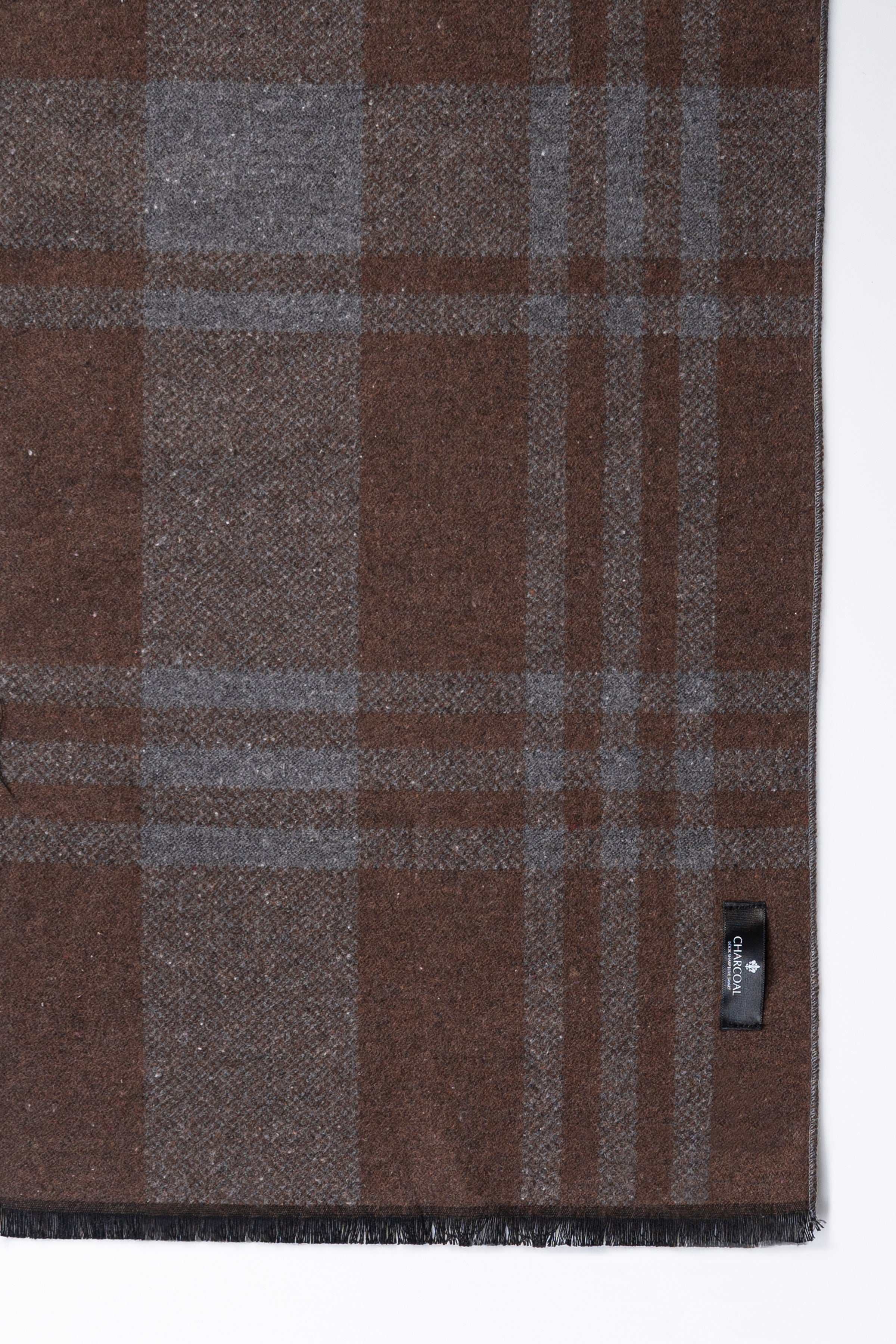 Brown plaid scarf fabric with small stitched tag detail.