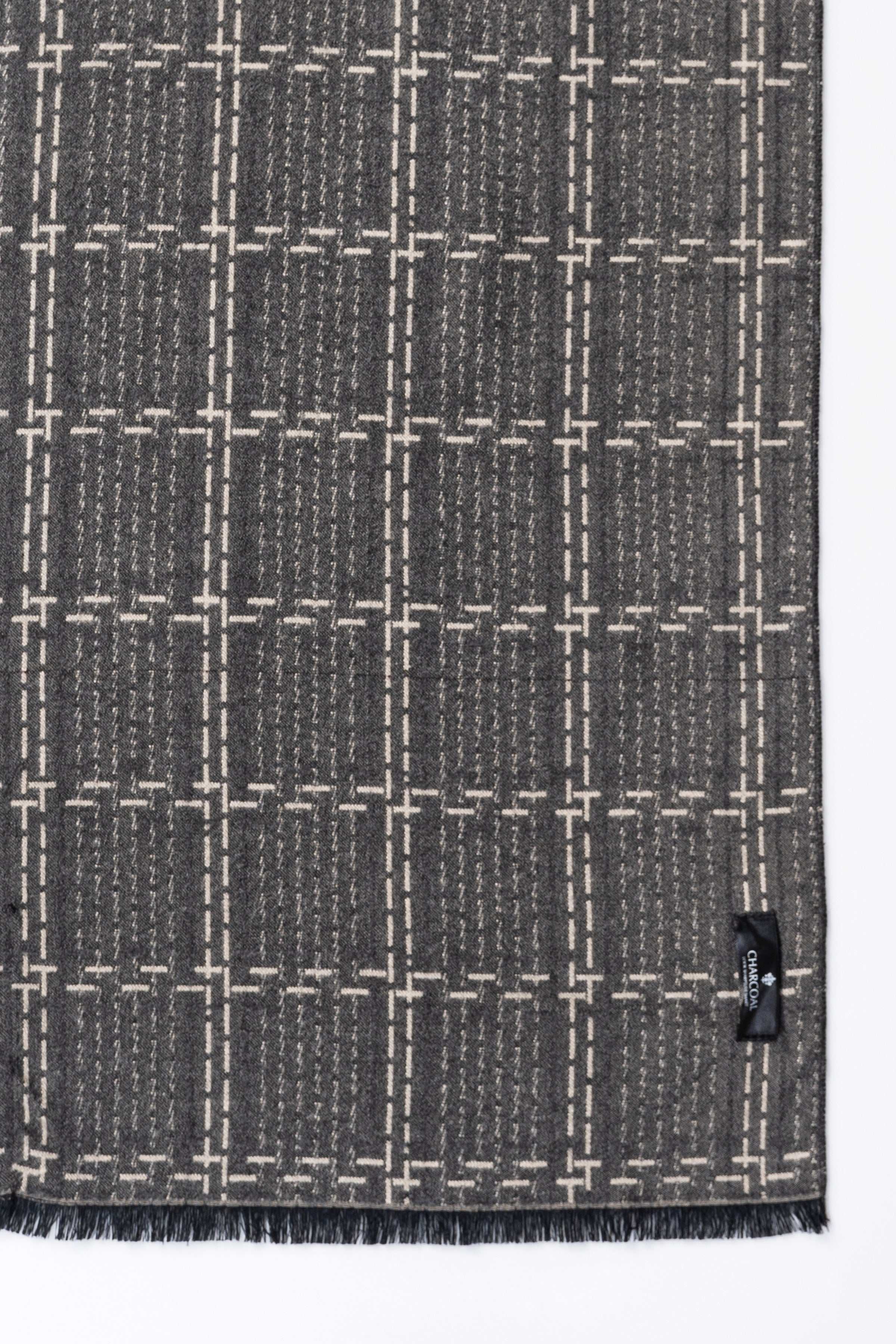 Close-up of dark gray scarf fabric with white grid stitching and small button.